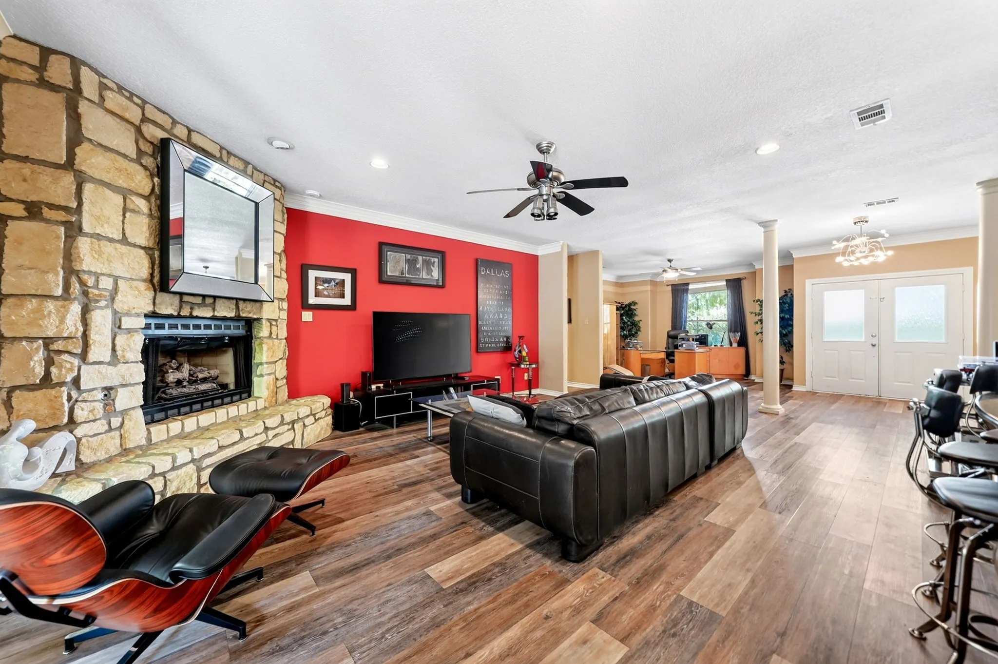 Spacious living area featuring a floor-to-ceiling stone fireplace, wood-finish flooring, recessed lighting, ceiling fan, and double entry doors