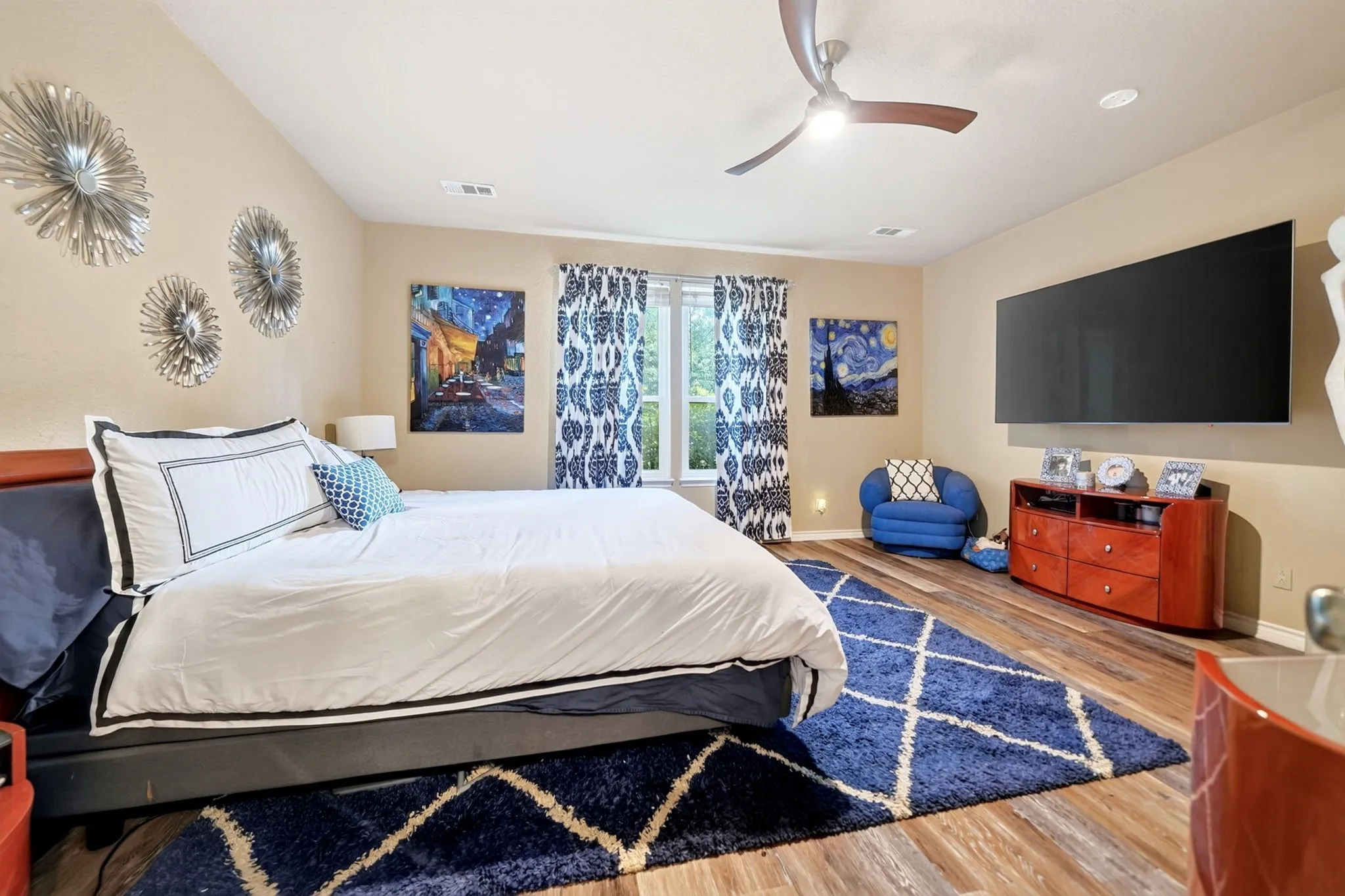 Spacious bedroom featuring wood-finish flooring, a contemporary ceiling fan, and recessed lighting