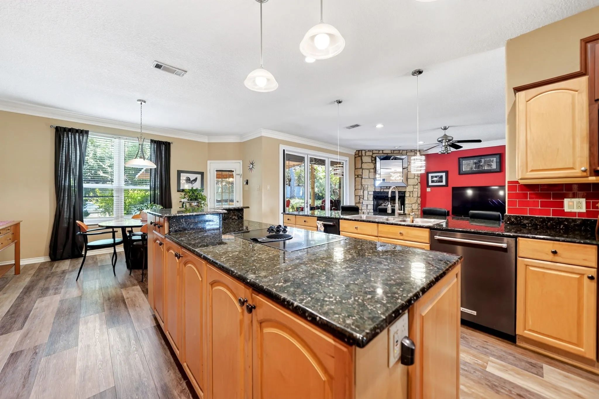Spacious kitchen featuring a large granite-topped island, light wood cabinetry, and wood-finish flooring