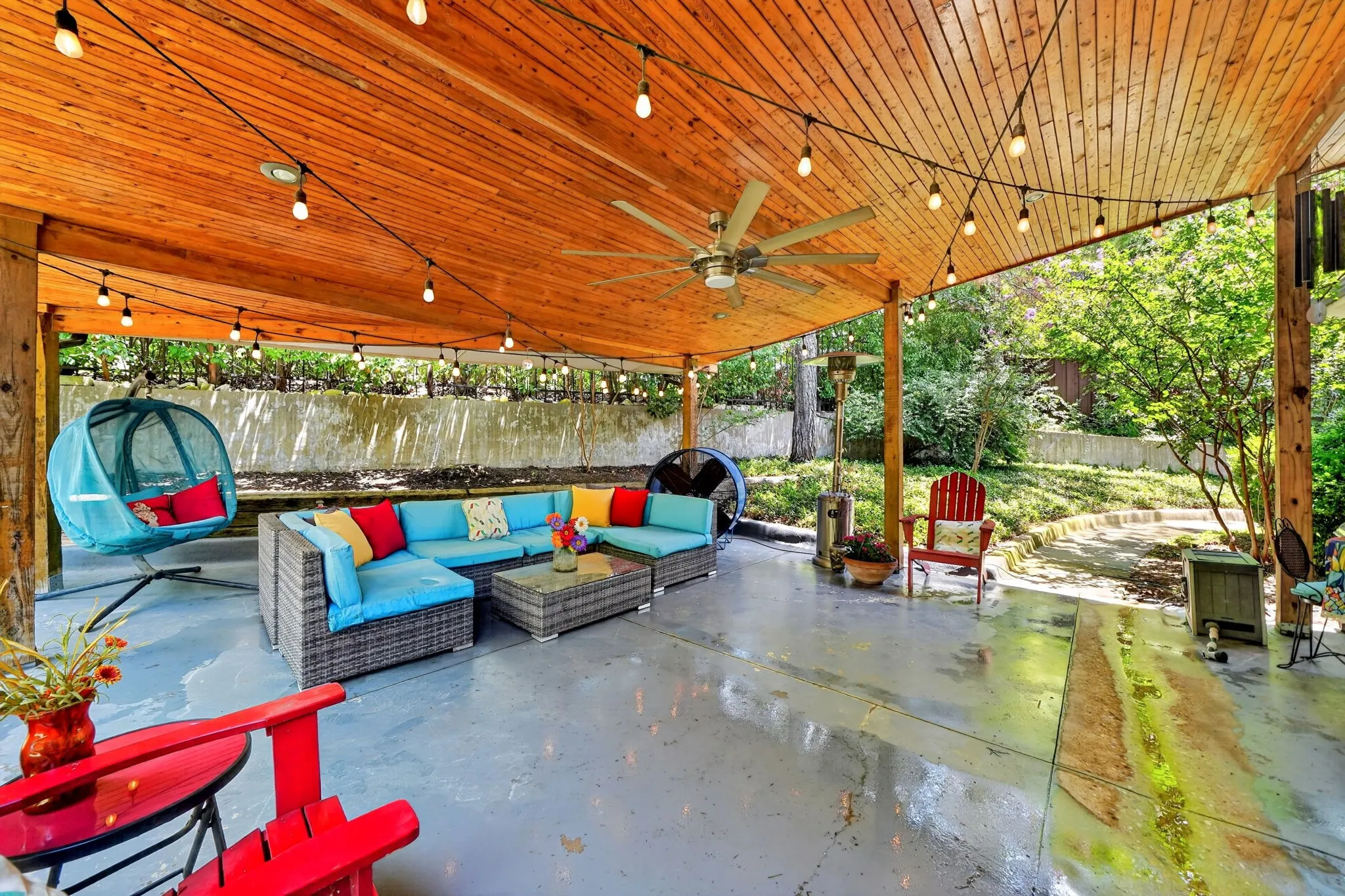 Expansive covered patio featuring a wood-panel ceiling, string lighting, and a ceiling fan