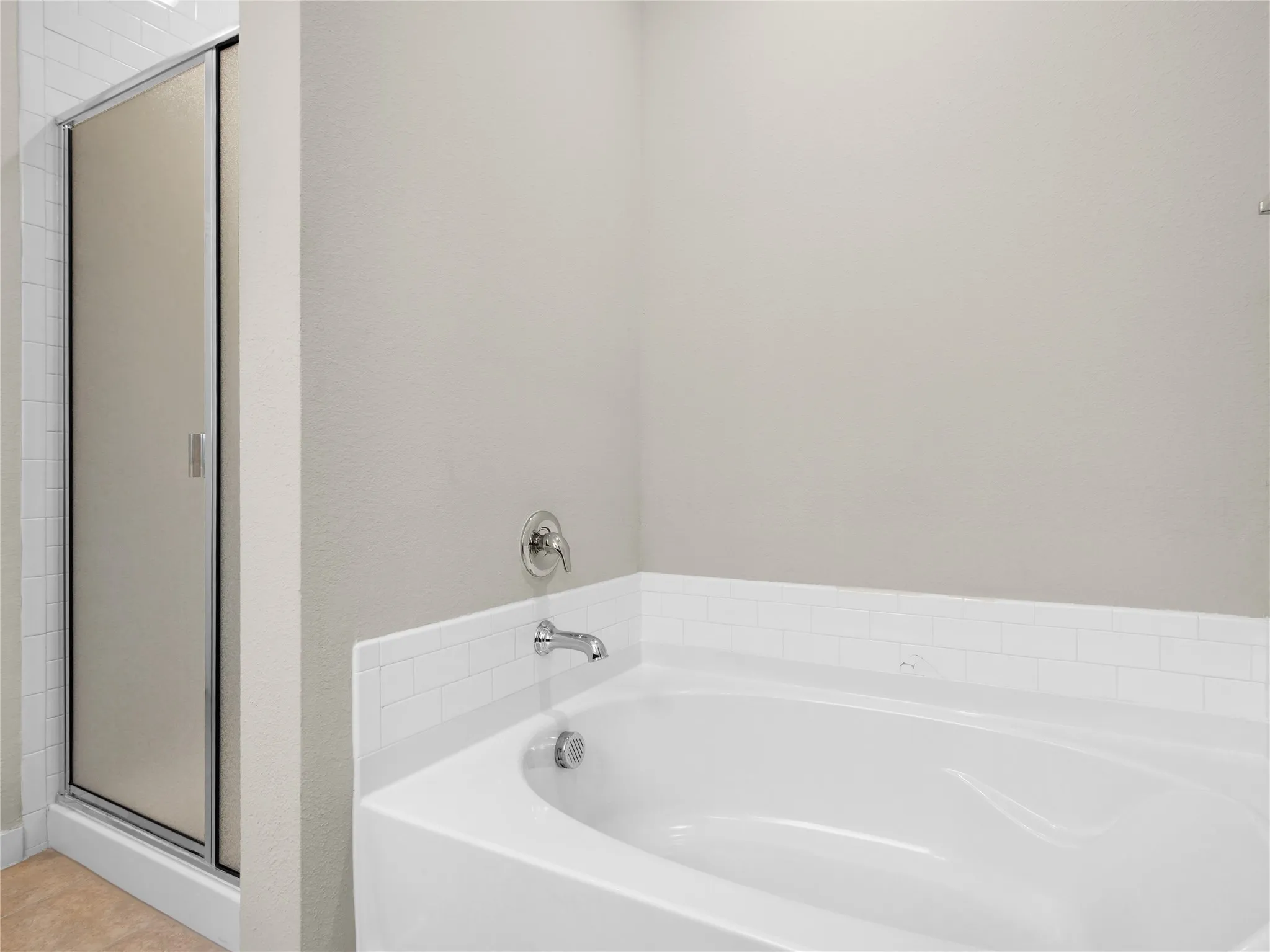 Built-in white bathtub with chrome fixtures and subway tile surround