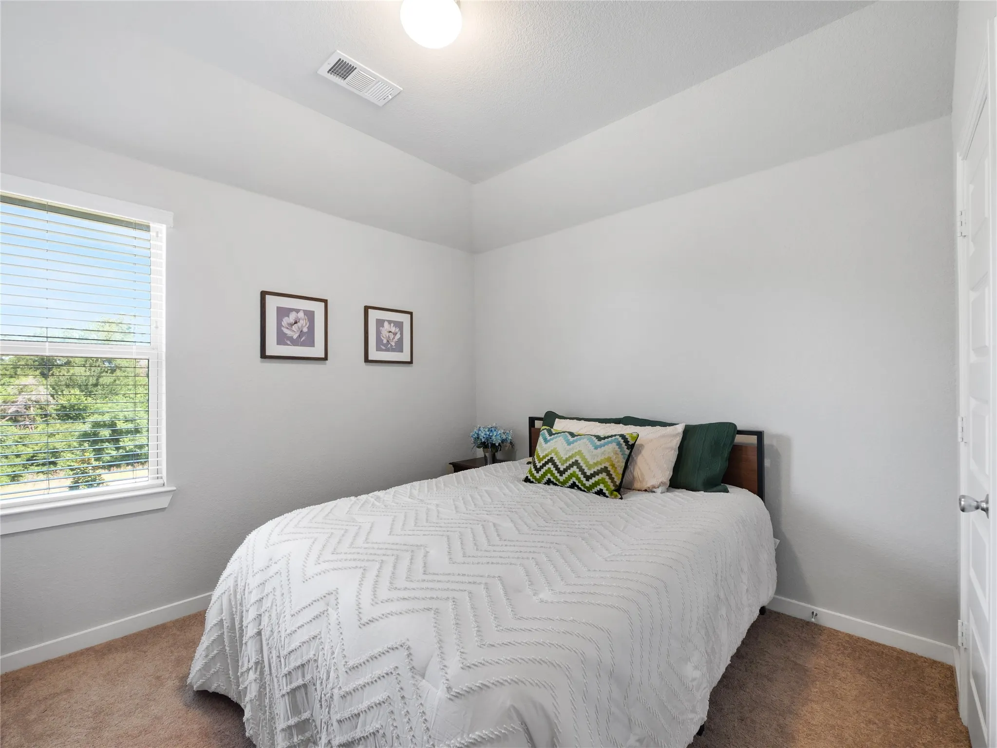 Carpeted room featuring a single window with blinds, a white paneled door, and a textured vaulted ceiling