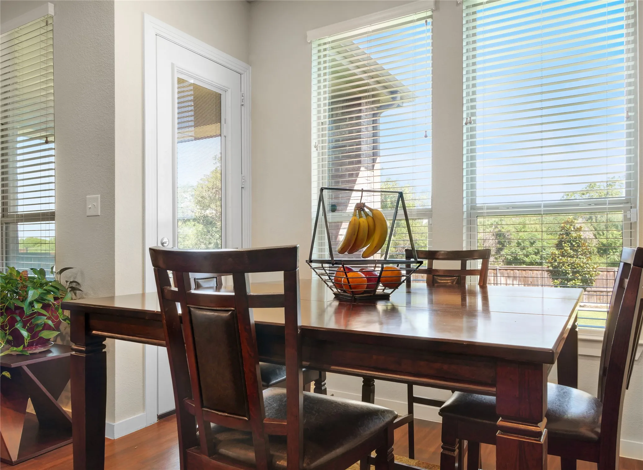 Dining area featuring wood-finish flooring, a glass-paned exterior door, and multiple large windows with horizontal blinds