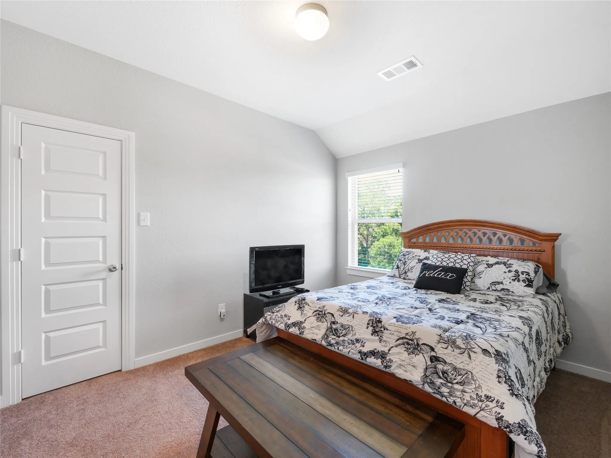 Carpeted bedroom featuring a window with blinds, a white paneled door, and neutral wall paint