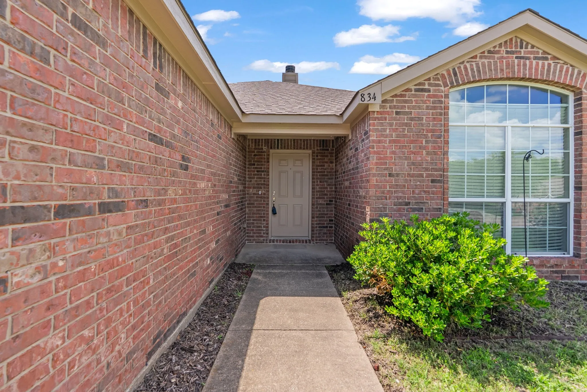 Brick exterior featuring a covered front entry and an arched window