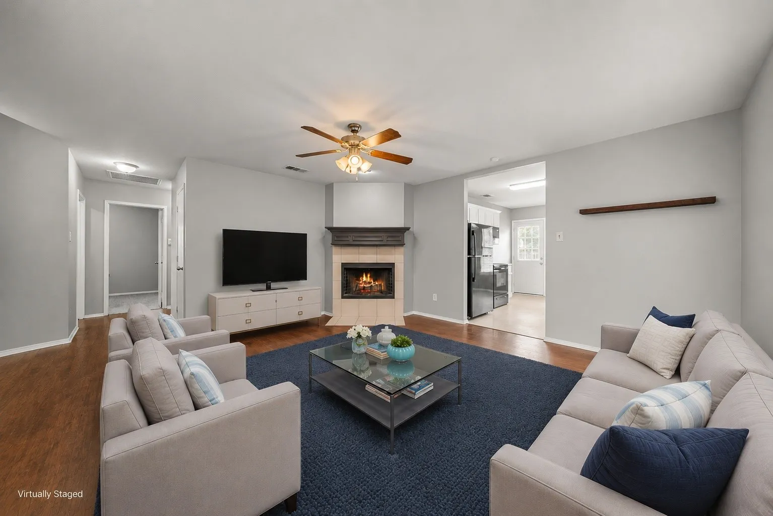 Spacious living area featuring a corner fireplace with tile surround, a built-in wood mantel, and wood-finish flooring
