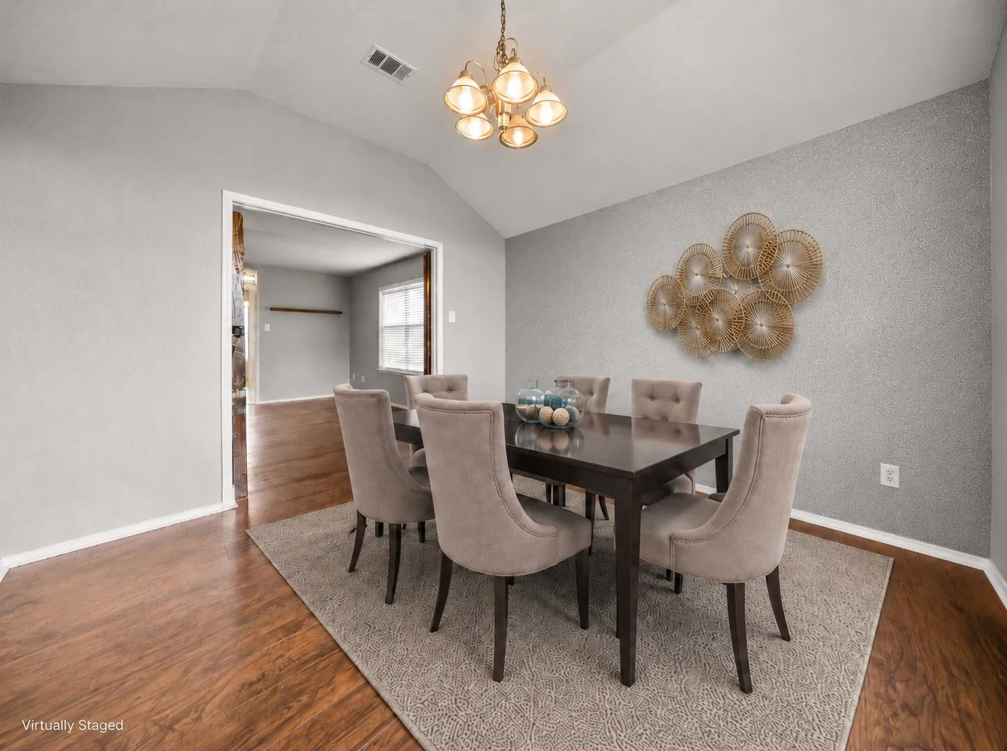 Dining area featuring wood-finish flooring, vaulted ceiling, and an open doorway
