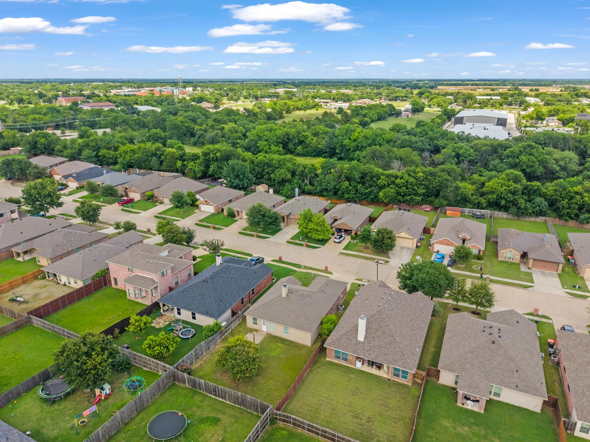 Aerial perspective showcasing a residential neighborhood with a variety of single-family homes, each featuring individual backyards with fencing
