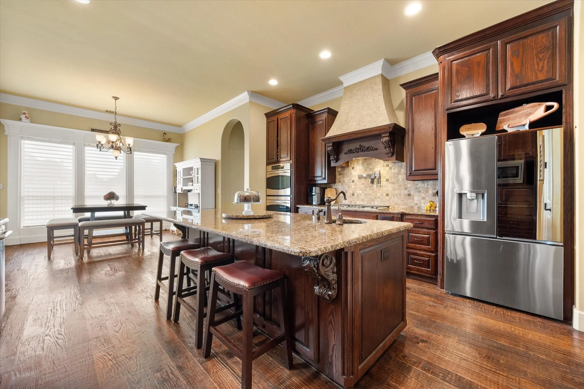 Kitchen featuring wood-finish flooring, custom wood cabinetry, and a stone-finish countertop island
