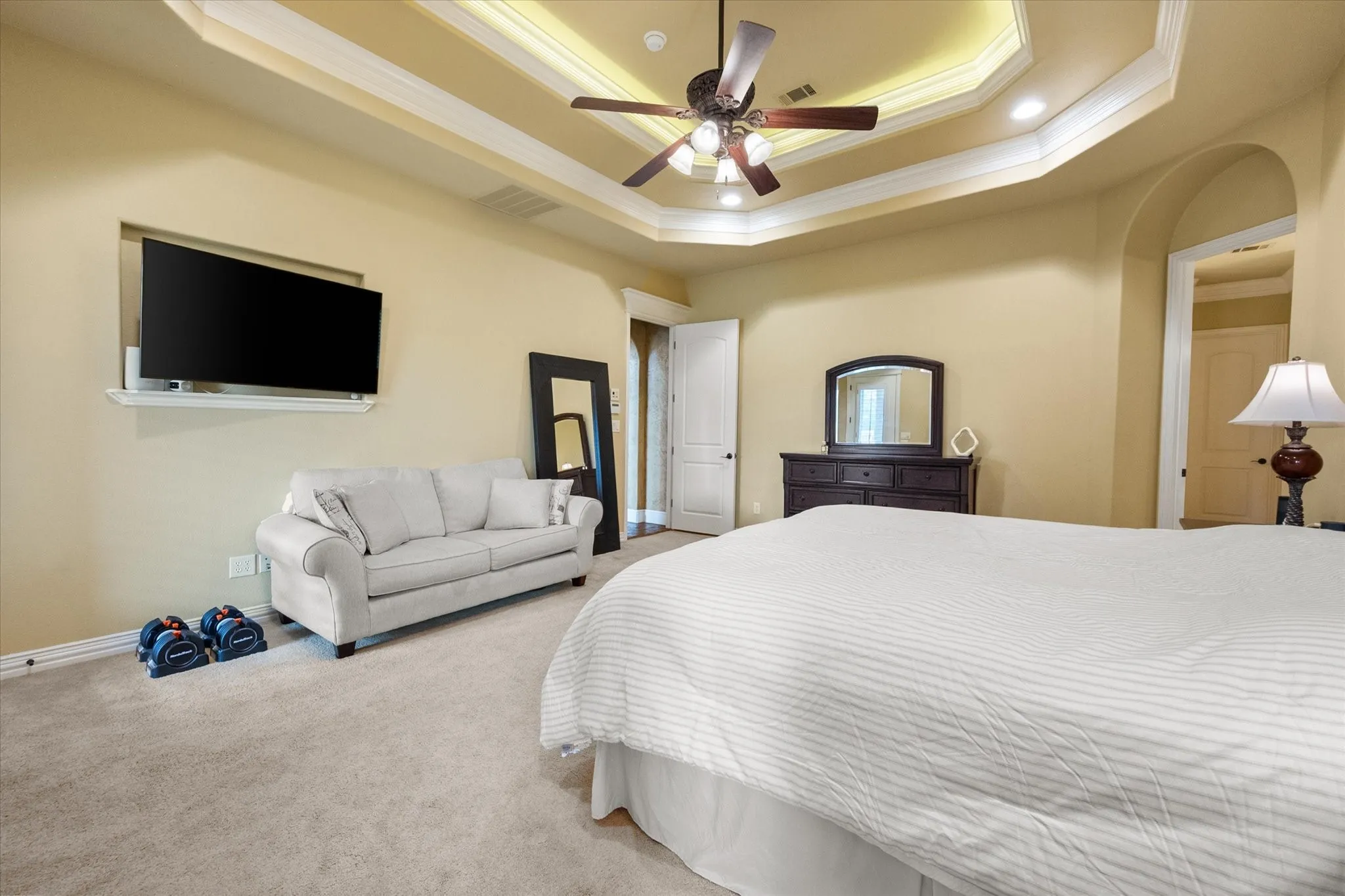 Carpeted room featuring a ceiling fan with light kit, tray ceiling with cove lighting, and recessed lighting