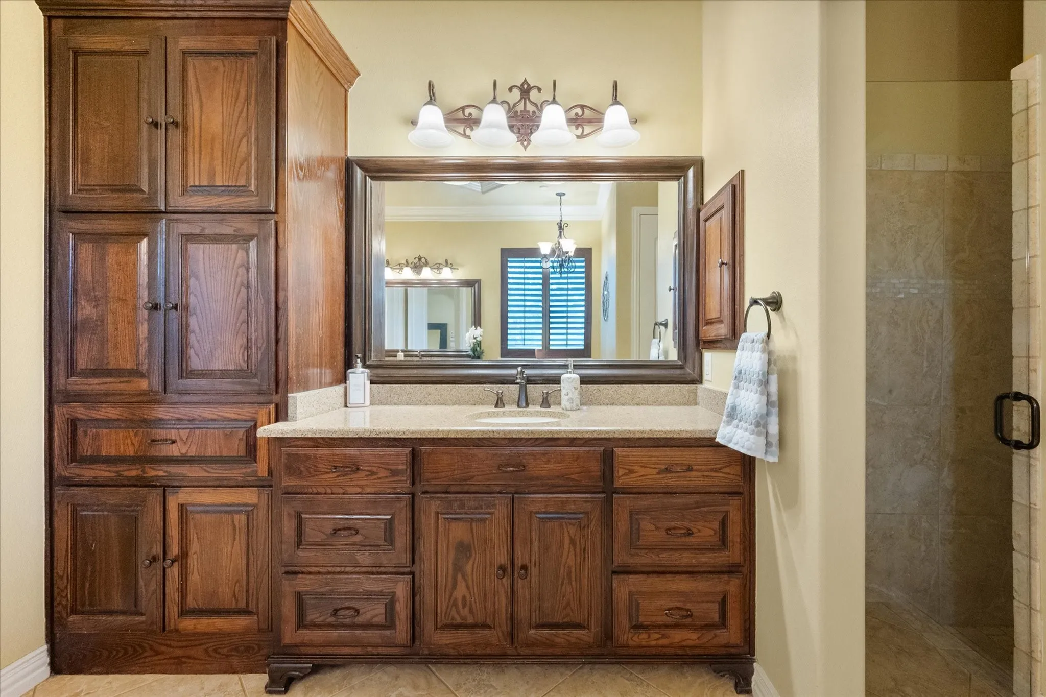 Bathroom featuring a vanity with wood-finish cabinetry, a stone-look countertop, an undermount sink, and an overhead light fixture