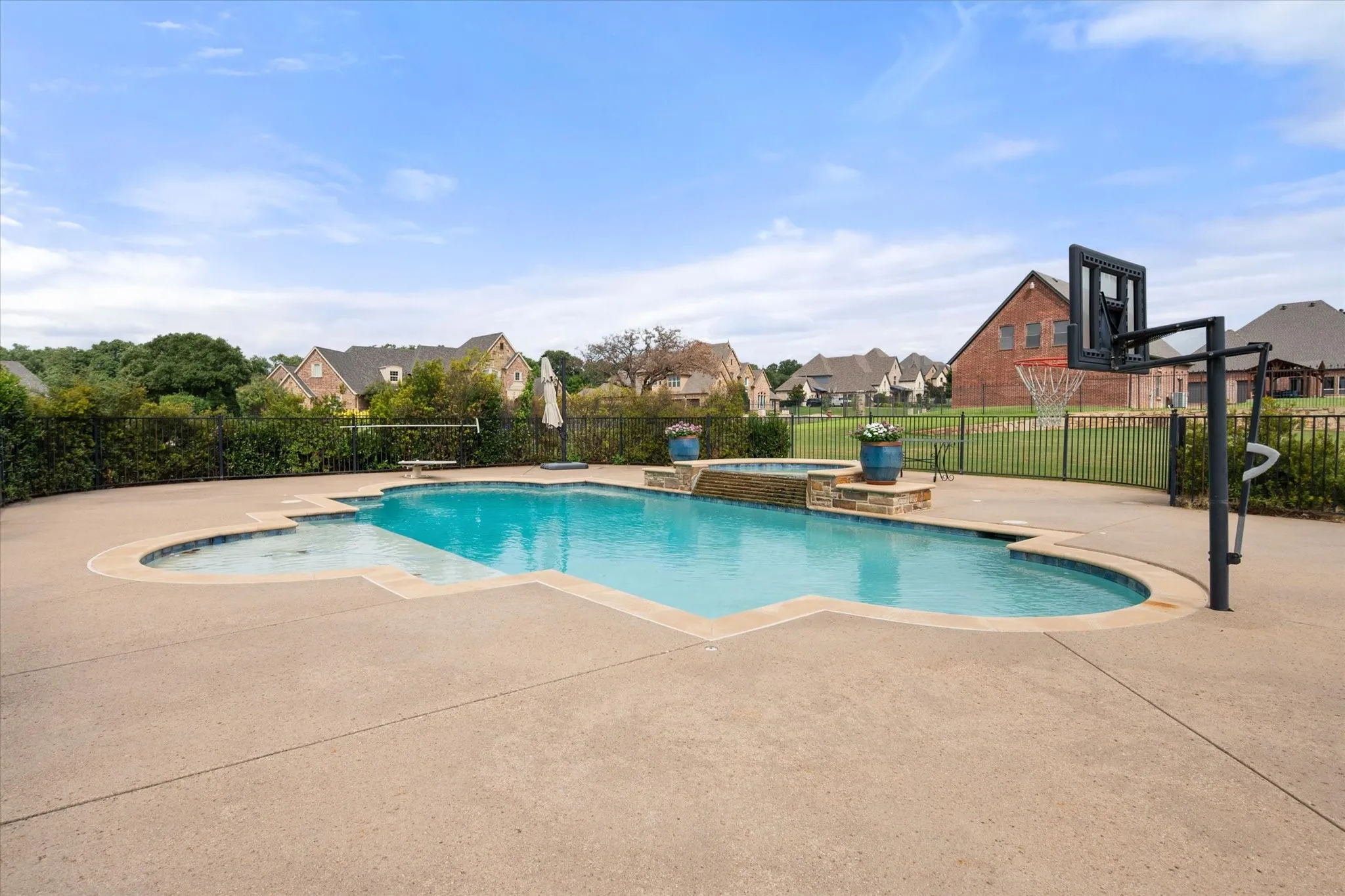 Freeform swimming pool with integrated spa and expansive concrete decking