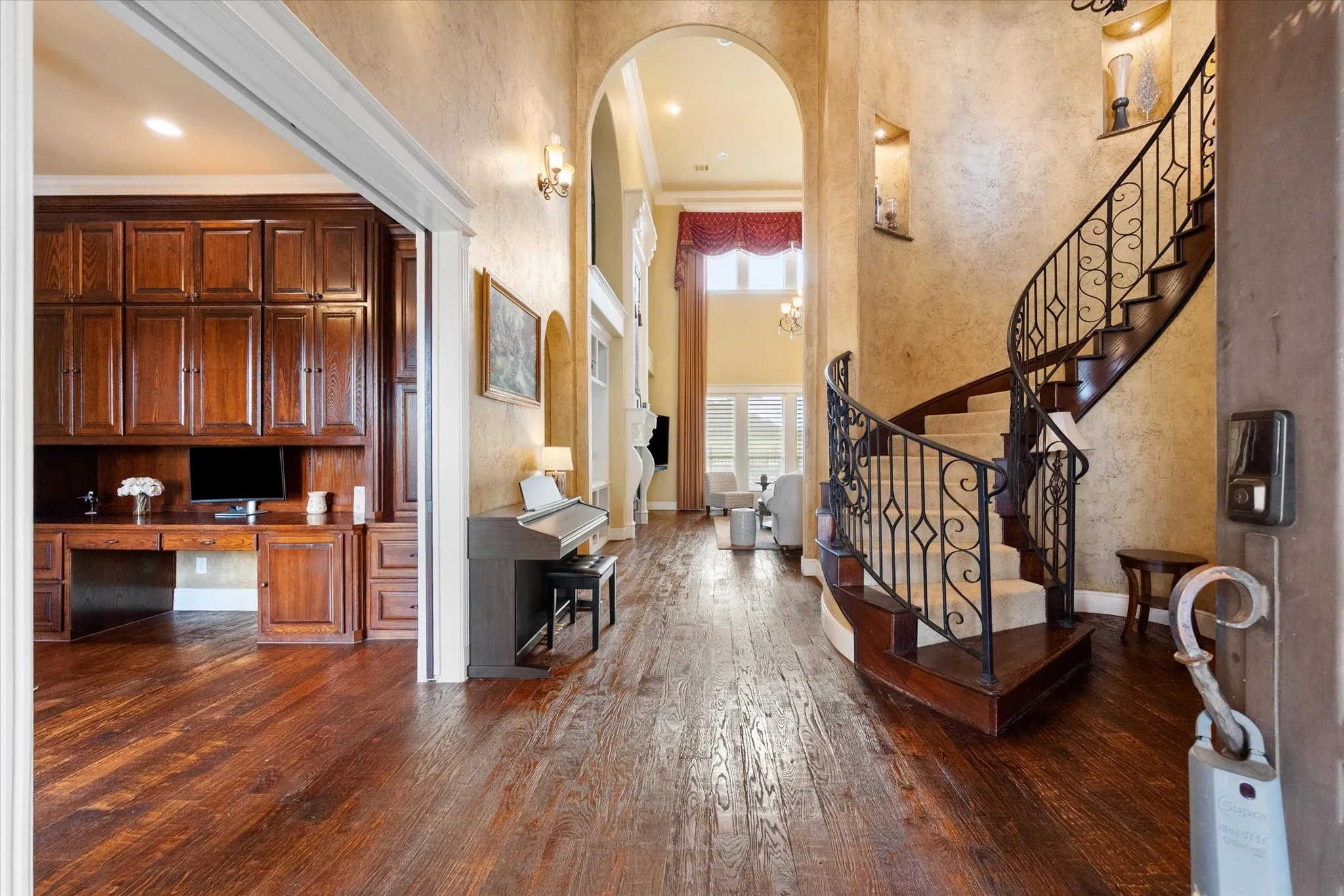Grand entryway featuring a curved staircase with wrought iron balusters and carpeted treads