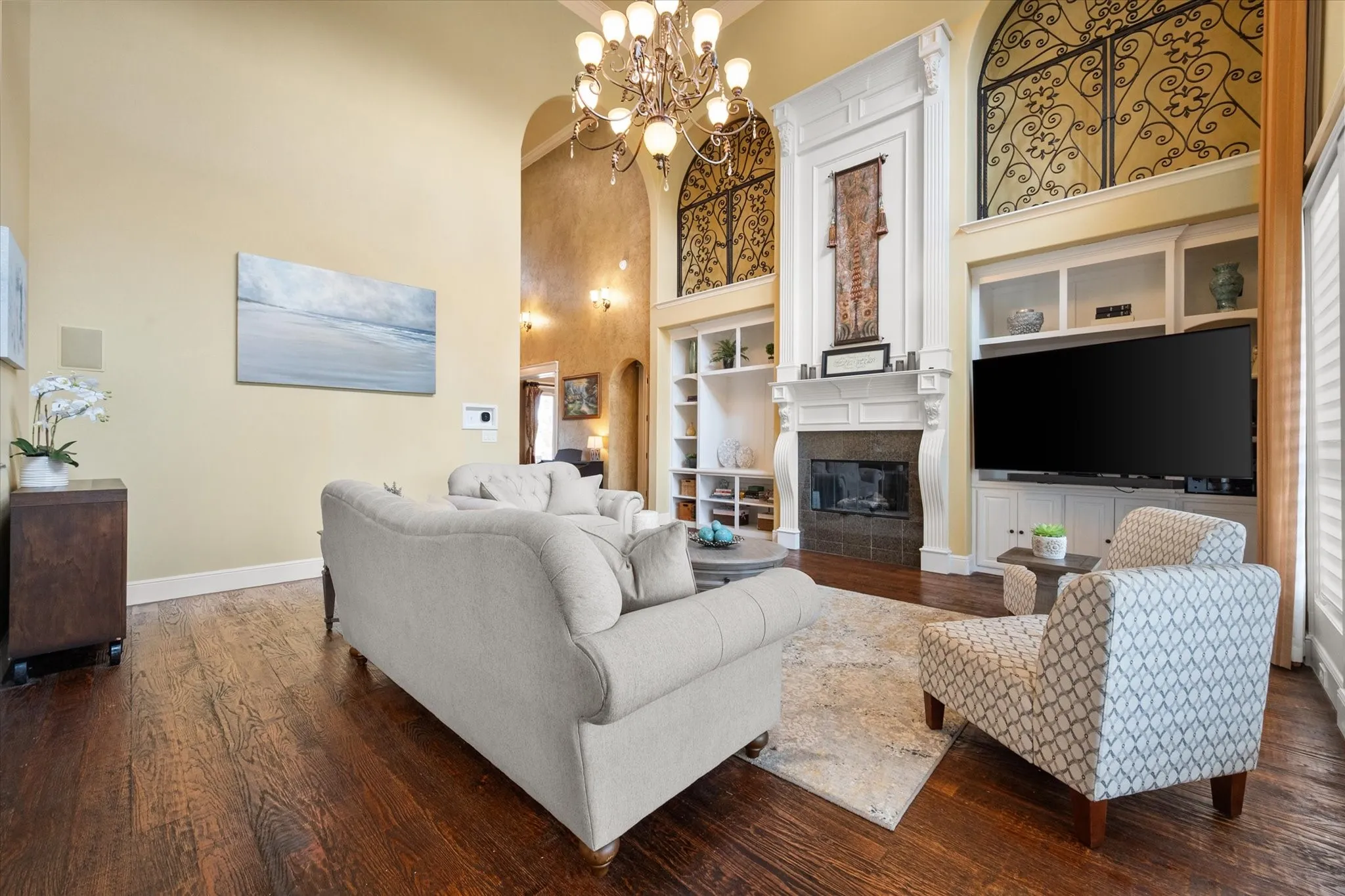 Spacious living area featuring high ceilings, dark wood-finish flooring, and a detailed fireplace with built-in shelving