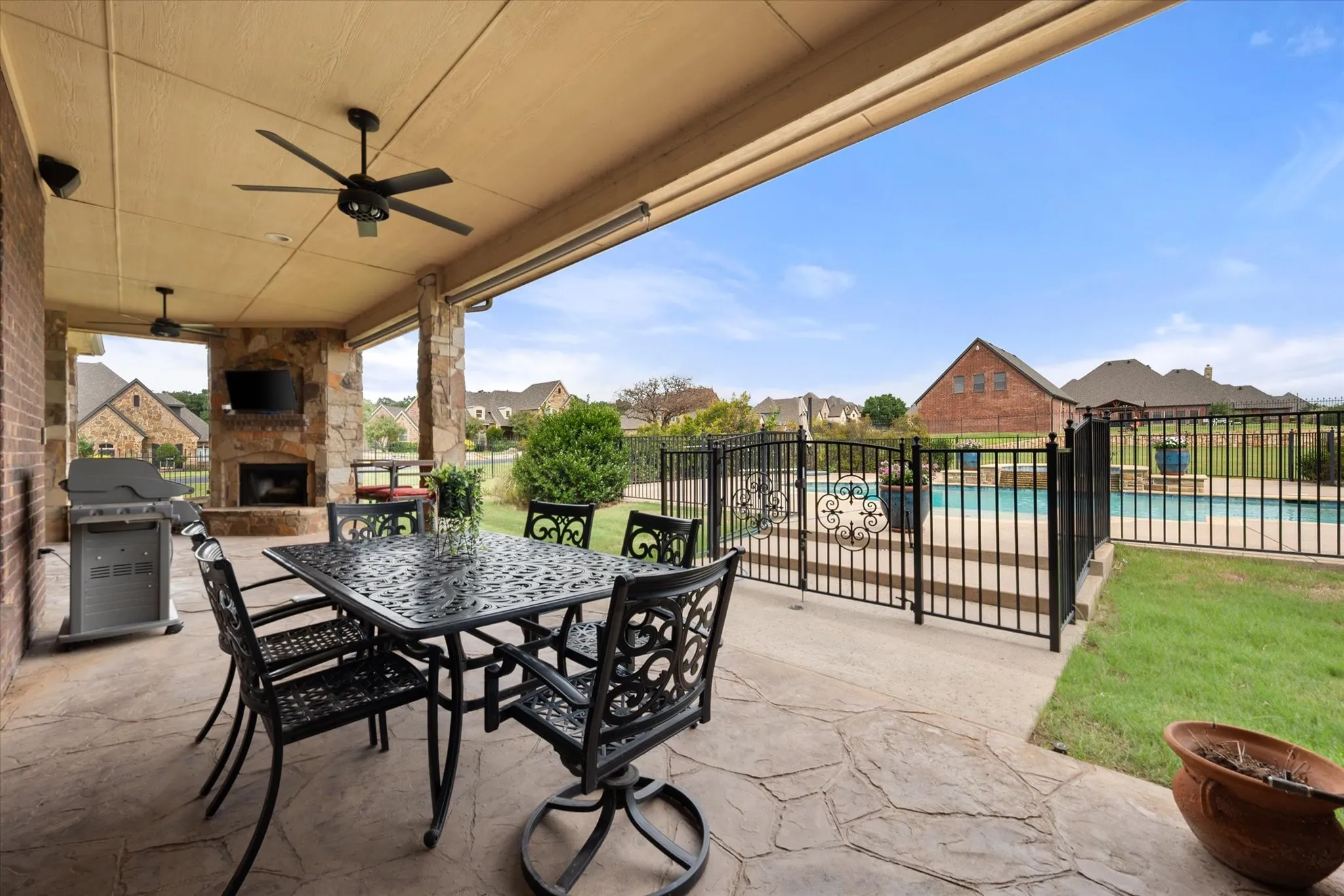 Expansive covered patio featuring a flagstone-style concrete surface, built-in fireplace with stone surround, and multiple ceiling fans. Also additional pool bath off patio.