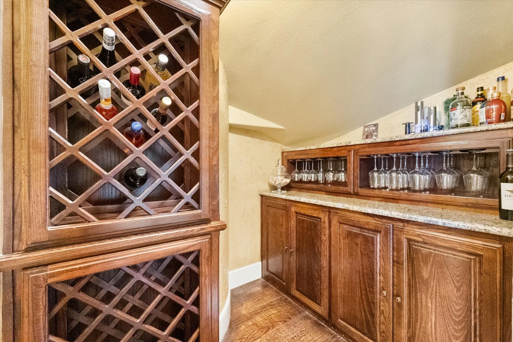 Custom built-in bar featuring wood-finish cabinetry, granite countertops, integrated glass racks, and a dedicated wine storage hutch