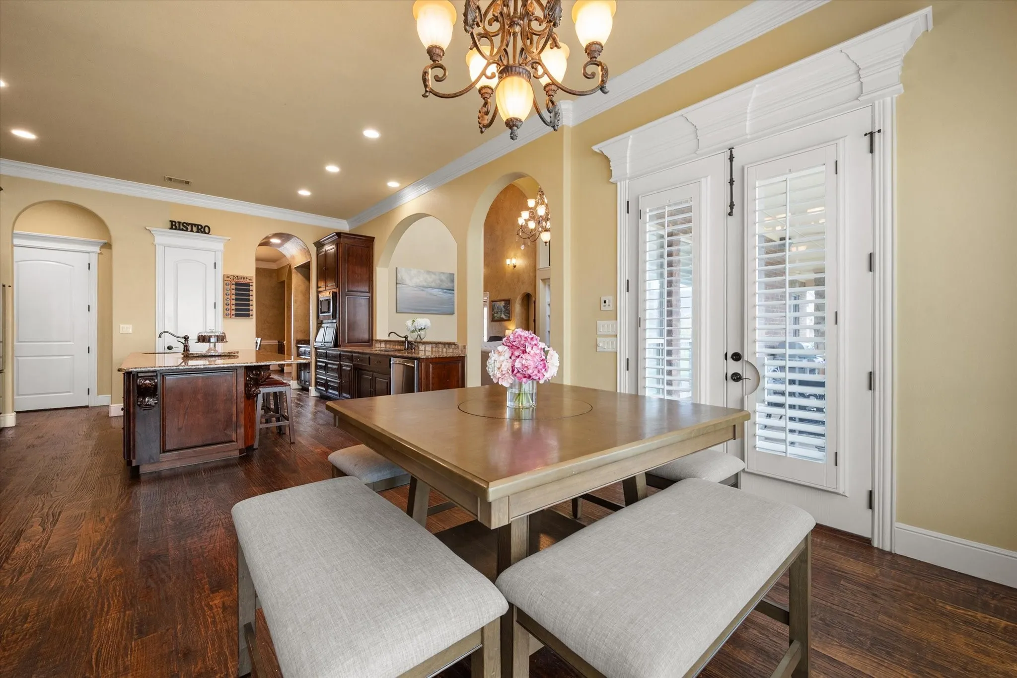 Dining area featuring dark wood-finish flooring, and white double doors with internal plantation shutters