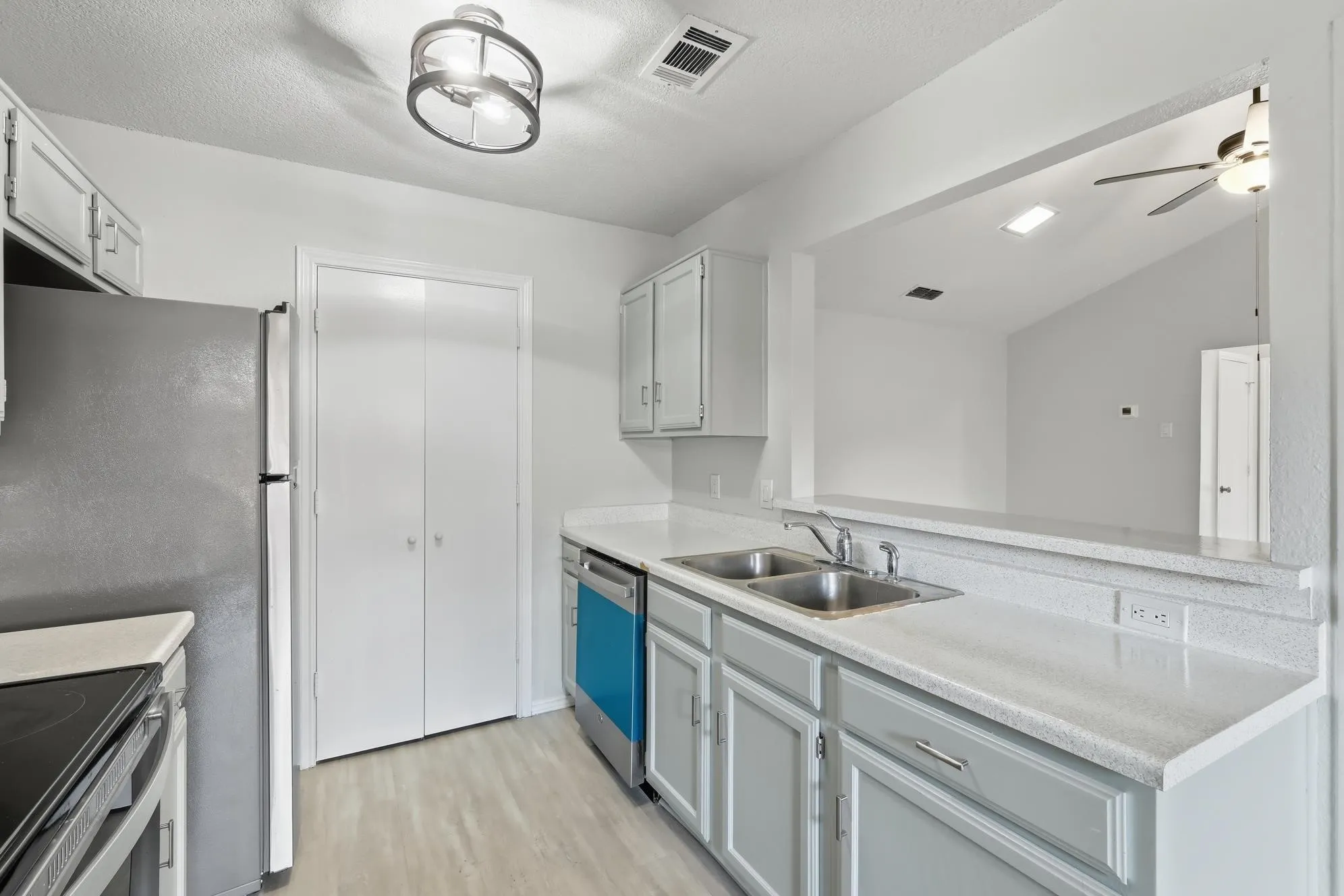 Kitchen featuring light grey cabinetry, white countertops, a double basin sink, and wood-finish flooring