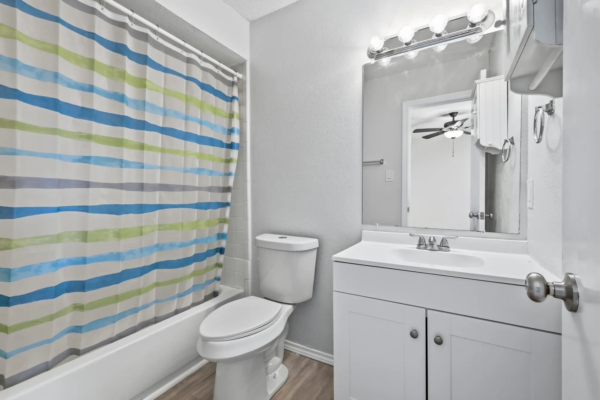 Bathroom featuring a white vanity with integrated sink, chrome faucet, and overhead bar lighting