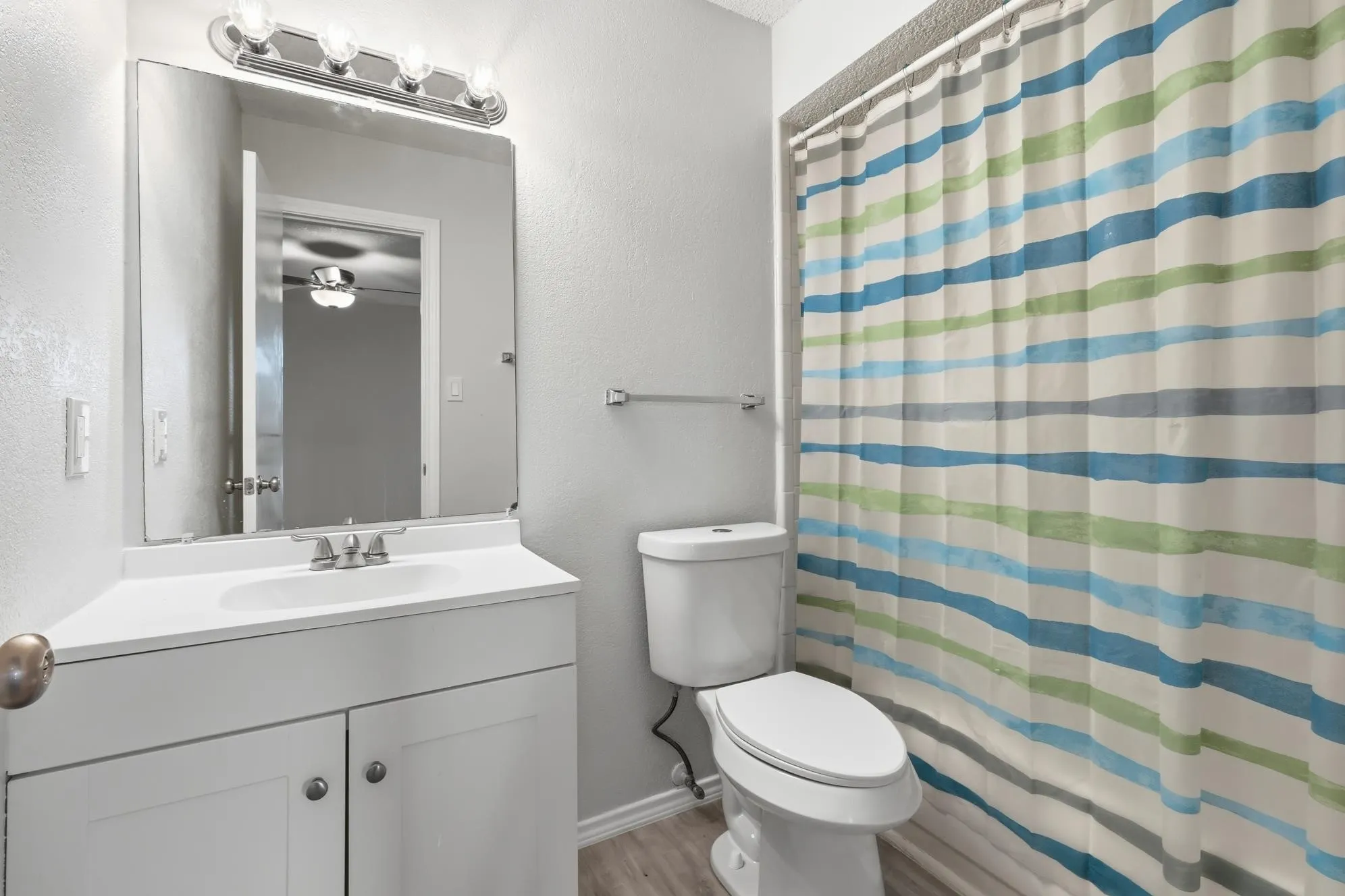 Bathroom featuring a white vanity with integrated sink, chrome faucet, and rectangular mirror with chrome light fixture