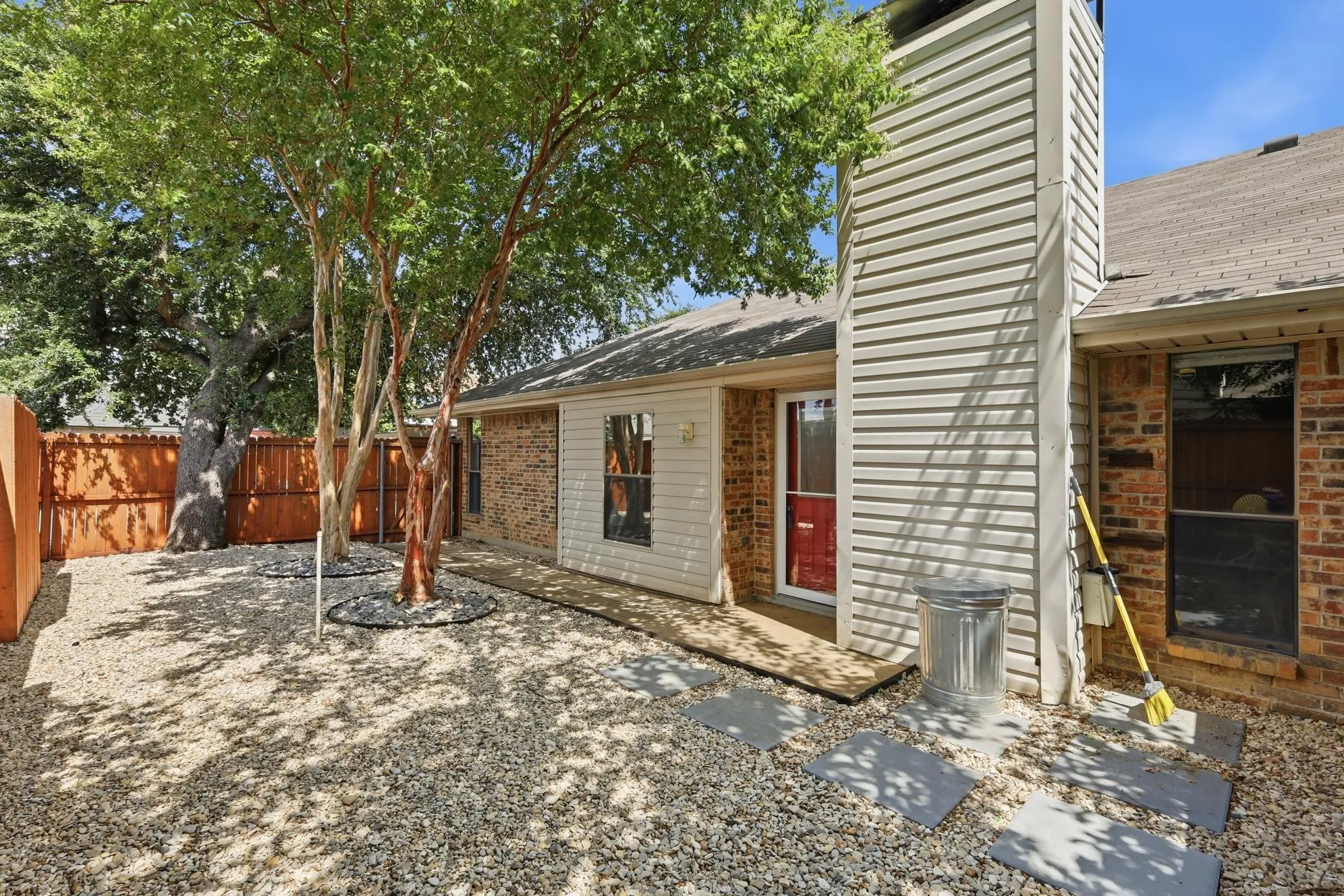 Private fenced backyard showcases established trees, attractive low-maintenance landscaping, and a cozy patio ideal for outdoor living year-round.
