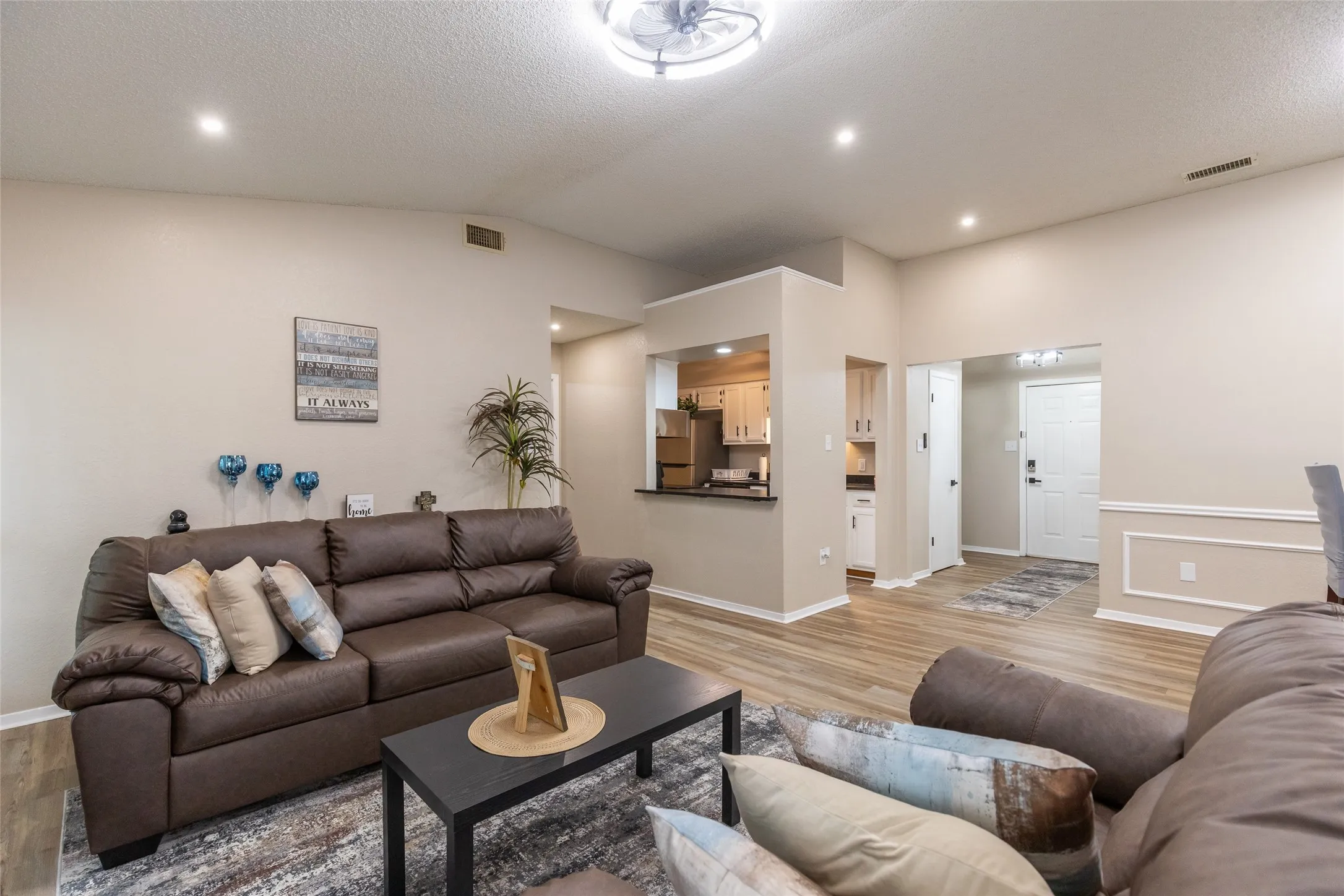 Vaulted ceiling living area featuring recessed lighting, wood-finish flooring, and a pass-through opening to the kitchen