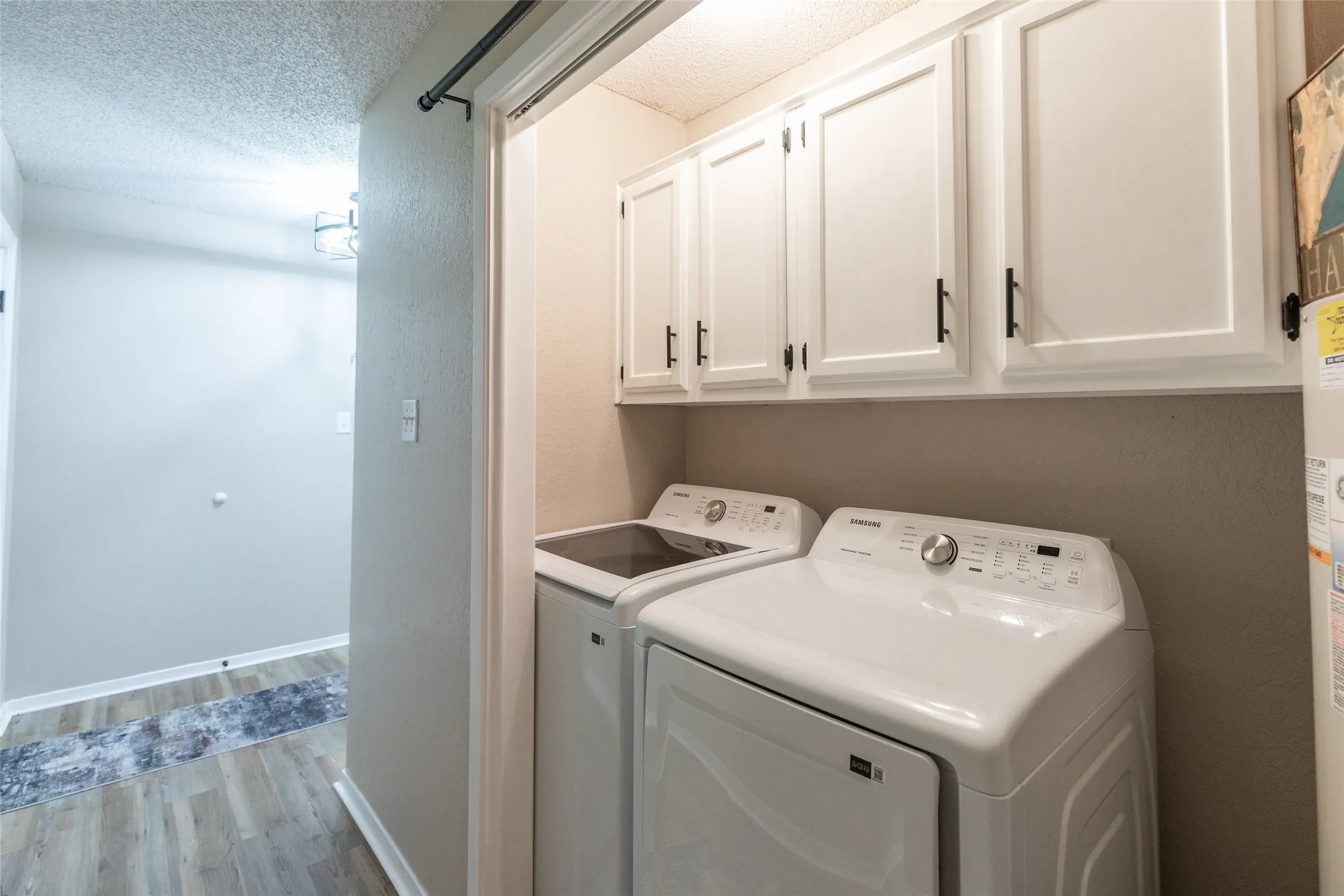 Dedicated laundry area featuring white shaker-style cabinetry with matte black hardware