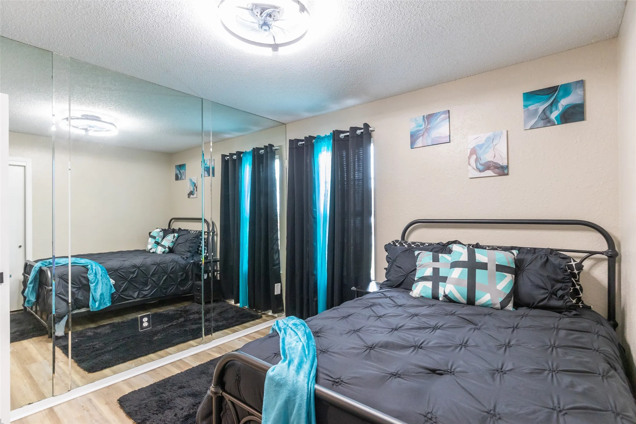 Bedroom 2 featuring a mirrored wall, wood-finish flooring, and a ceiling-mounted light fixture