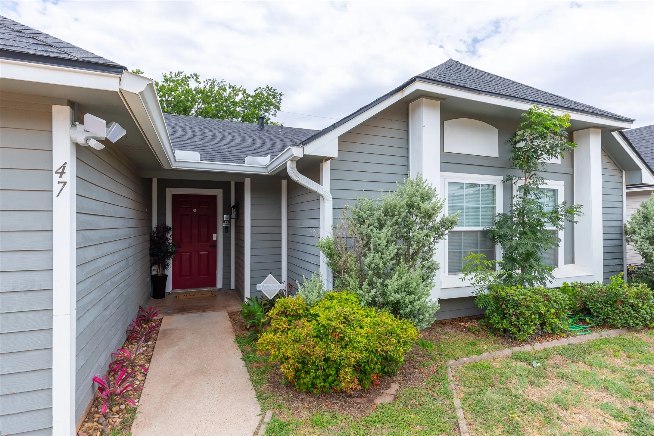 Gray siding exterior featuring a contrasting red entry door and white trim