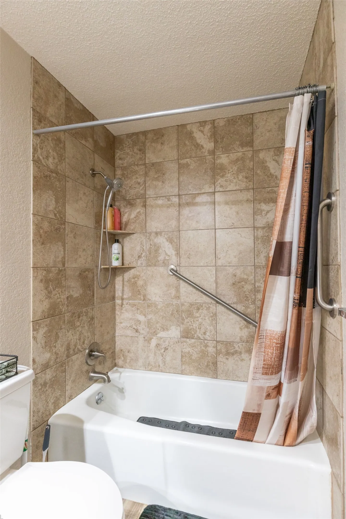 Bathroom 2 bathtub-shower combination featuring neutral-toned tiled surround