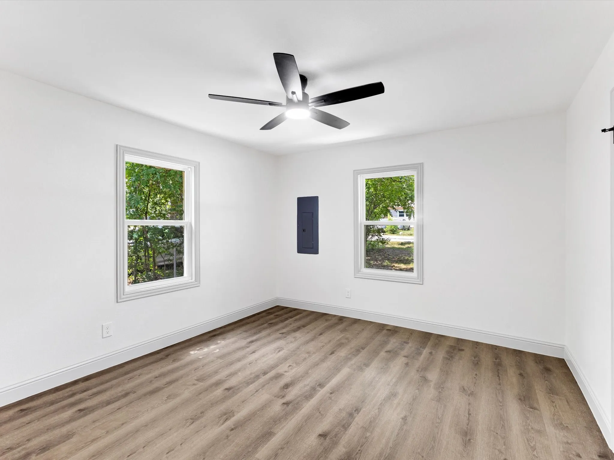 Room featuring wood-finish flooring, white walls, and white baseboards