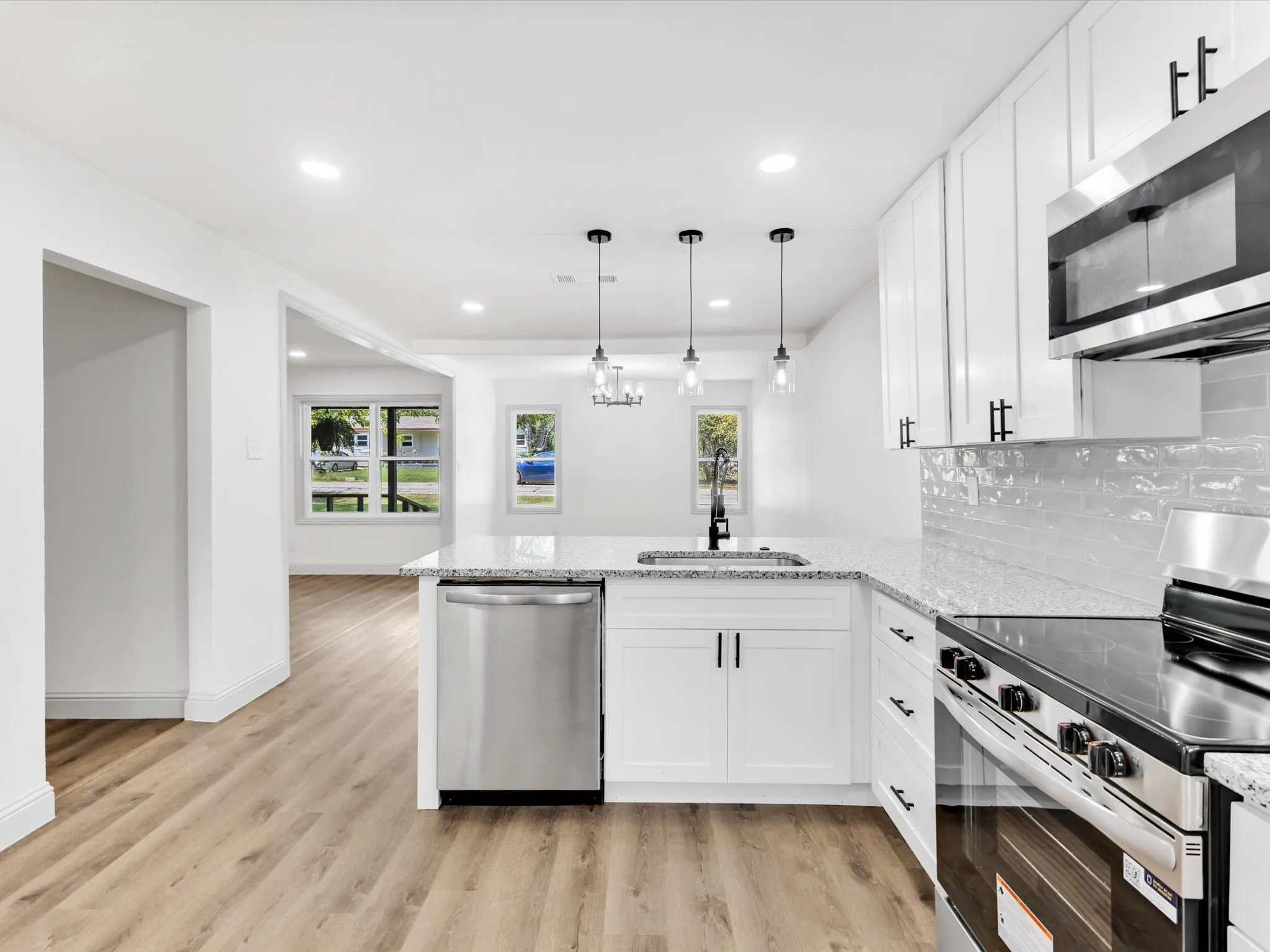 Modern kitchen featuring white shaker cabinetry, stainless steel appliances including a gas range and built-in microwave, and a center island with undermount sink