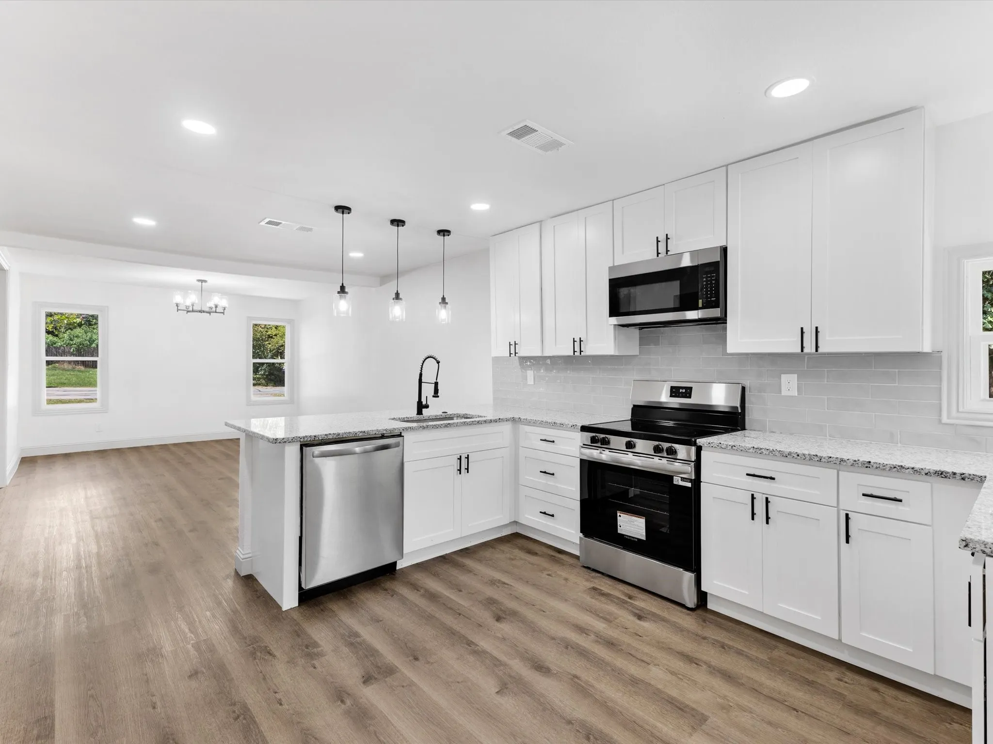 Kitchen featuring white shaker cabinetry, stainless steel appliances, speckled countertops, and a subway tile backsplash