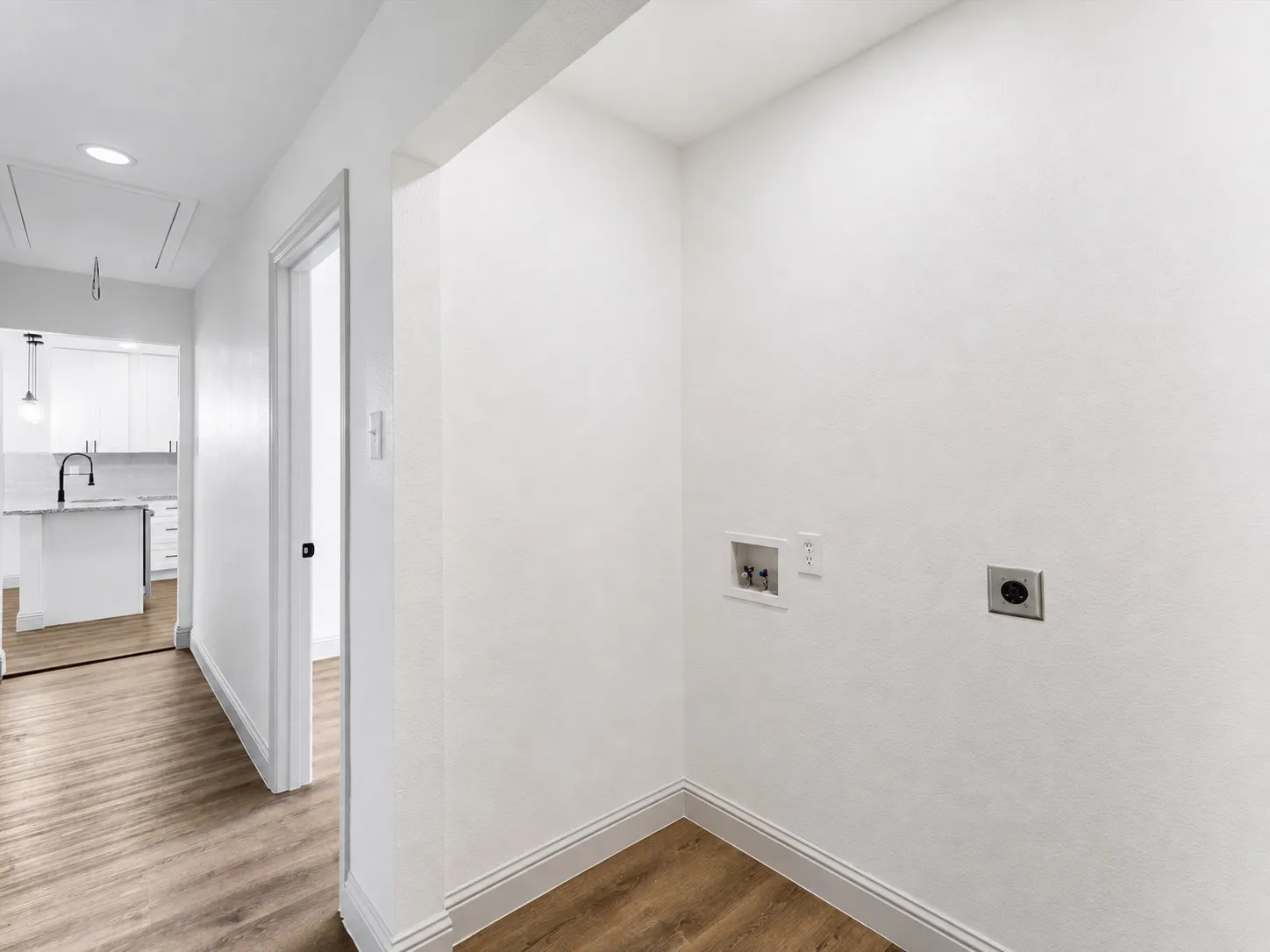 Dedicated laundry area with utility hookups, wood-finish flooring, and crisp white walls