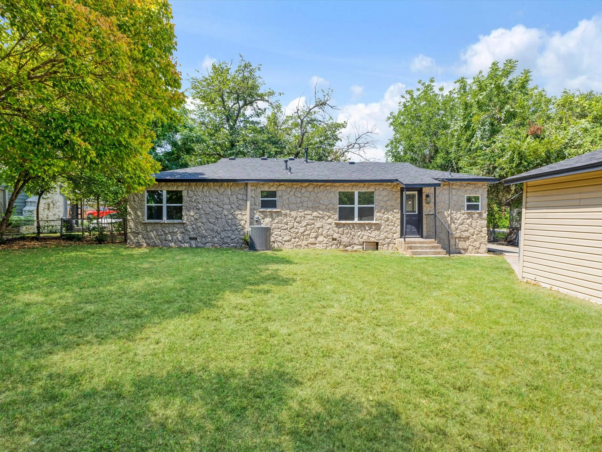 Stone exterior residence featuring a dark asphalt shingle roof