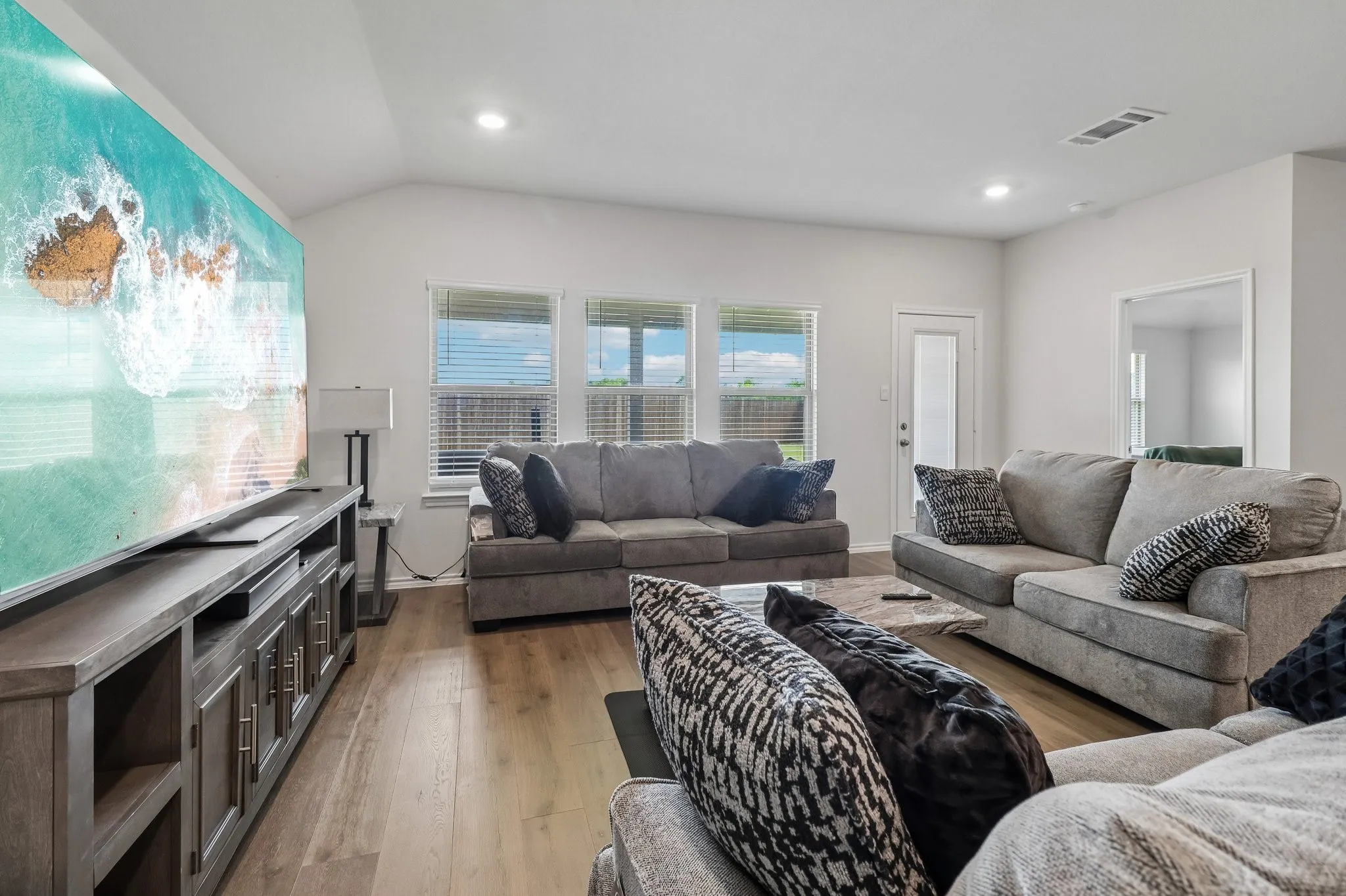Vaulted ceiling living space featuring wood-finish flooring and recessed lighting