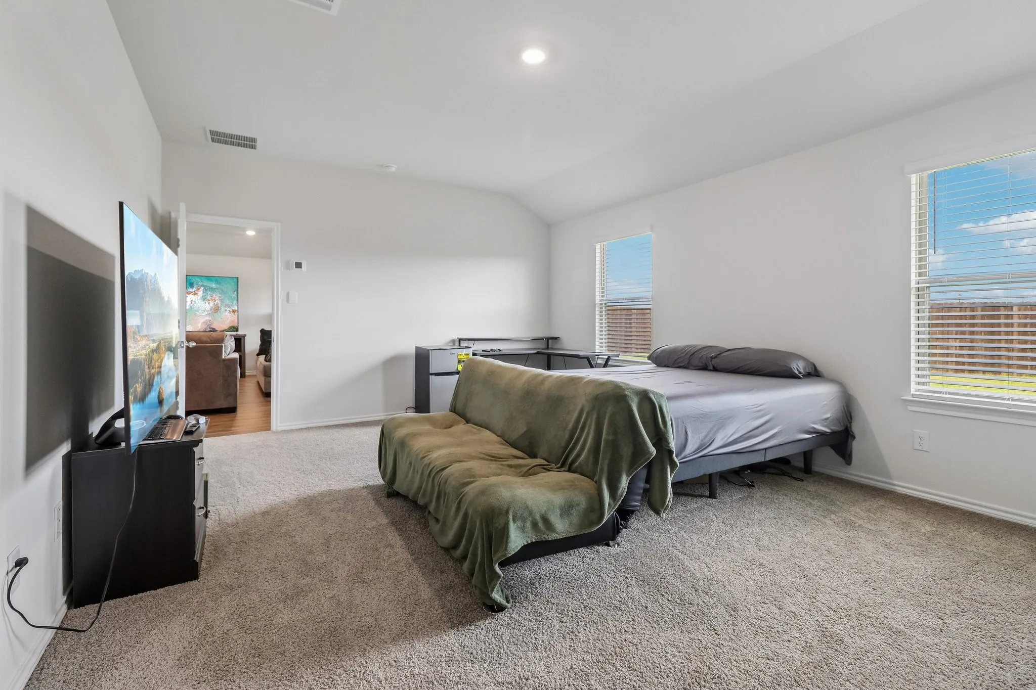 Carpeted room with vaulted ceiling and recessed lighting
