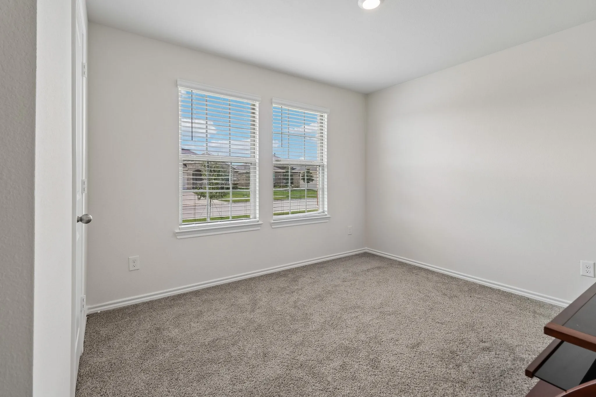 Room featuring two windows with horizontal blinds, neutral-toned carpeting, white baseboards, and a recessed ceiling light