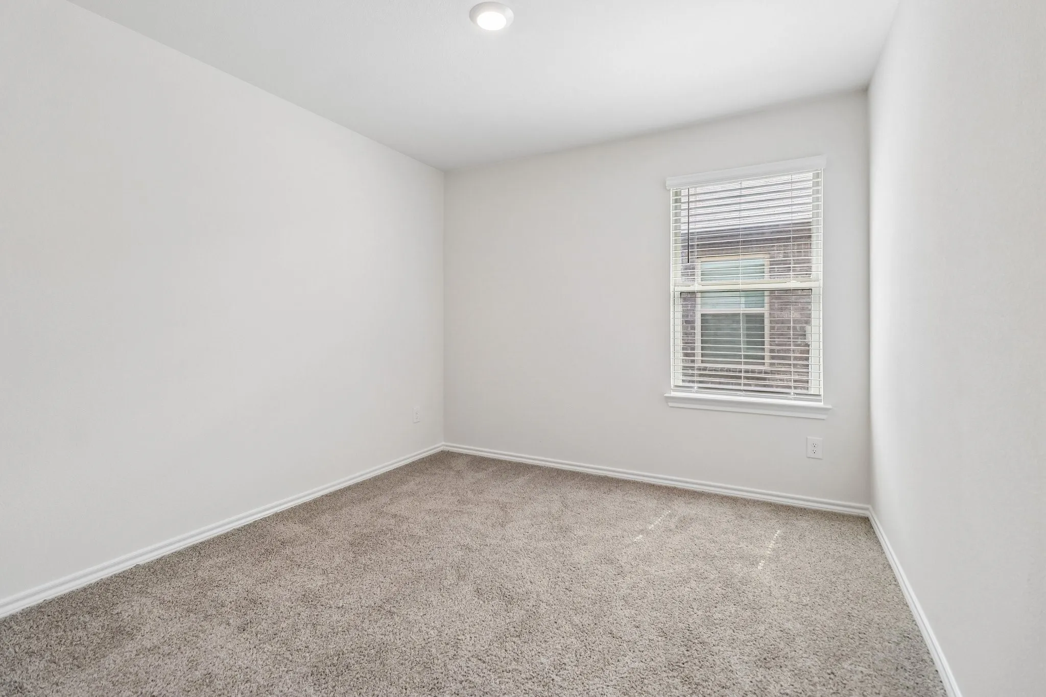 Recessed lighting illuminates neutral-toned carpeting and light-colored walls