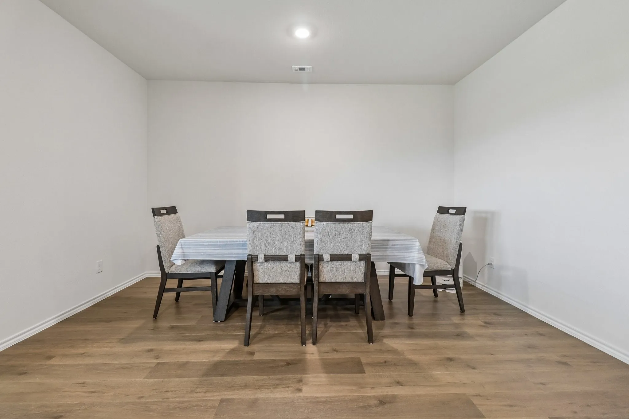 Spacious room featuring wood-finish flooring, white baseboards, and a recessed ceiling light