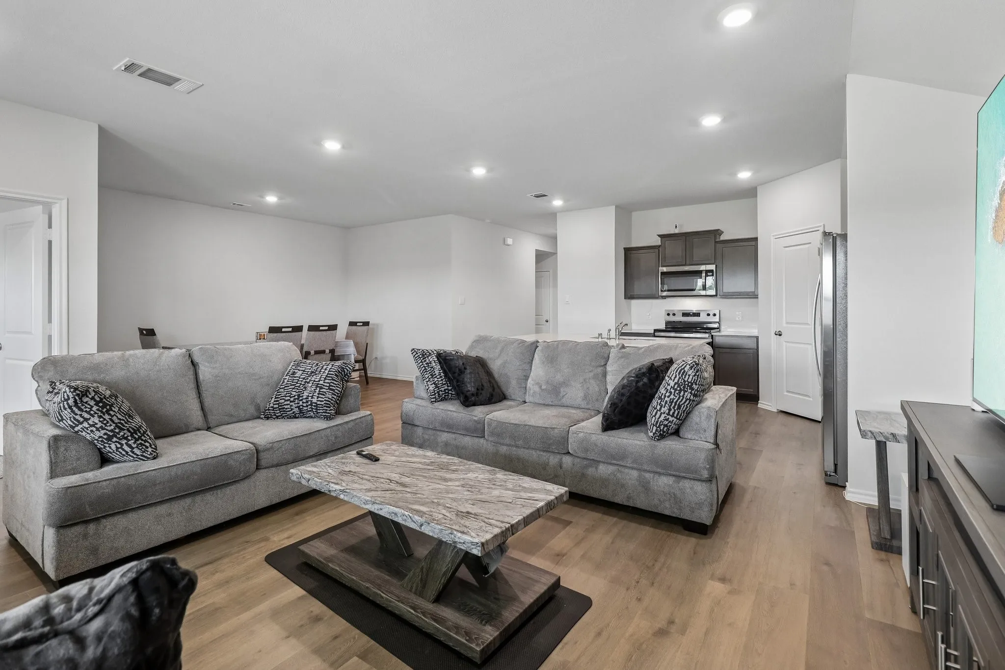 Open-concept living area with wood-finish flooring, recessed lighting, and white wall finishes