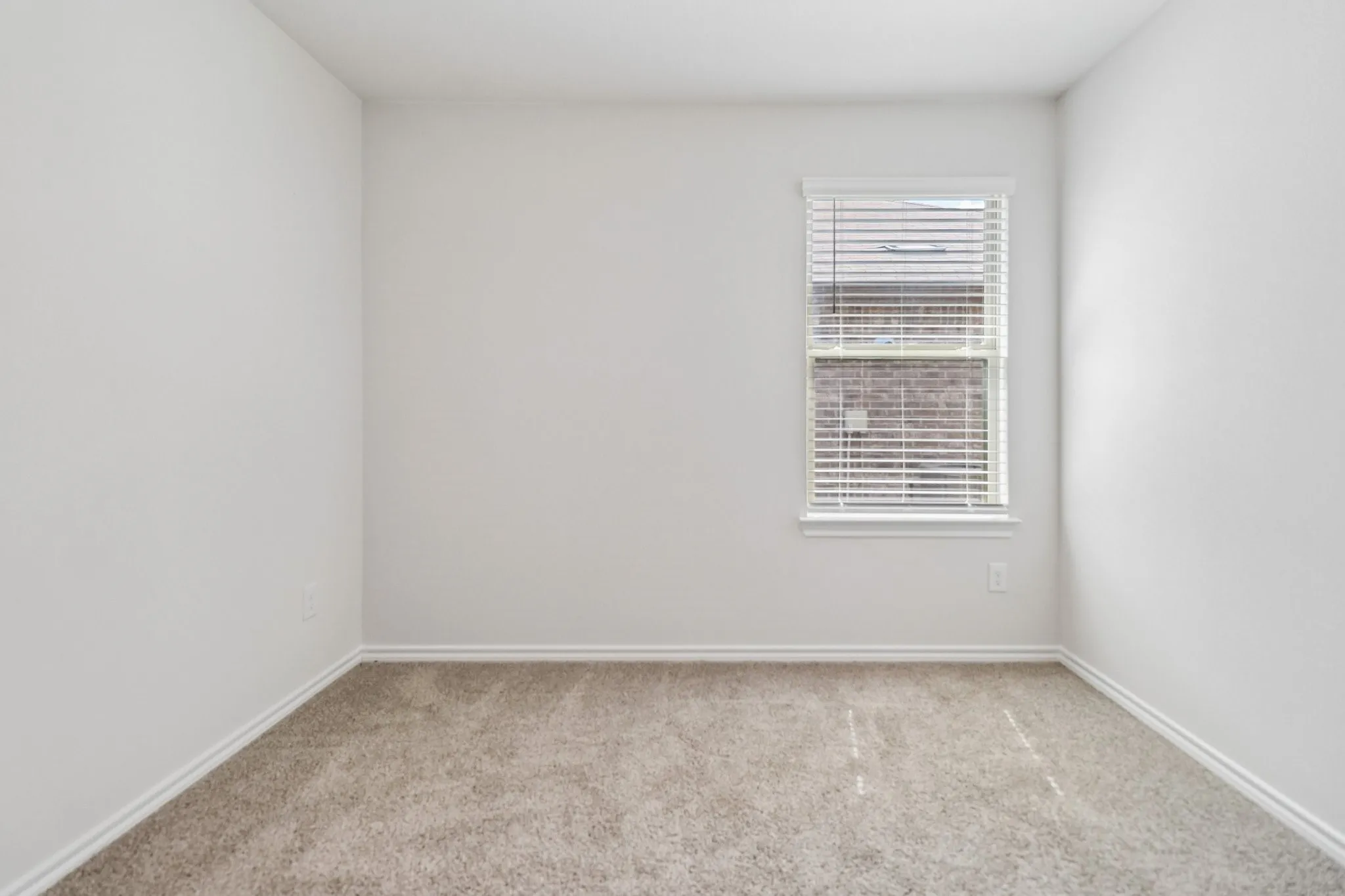 Neutral wall tones with a single window featuring horizontal blinds