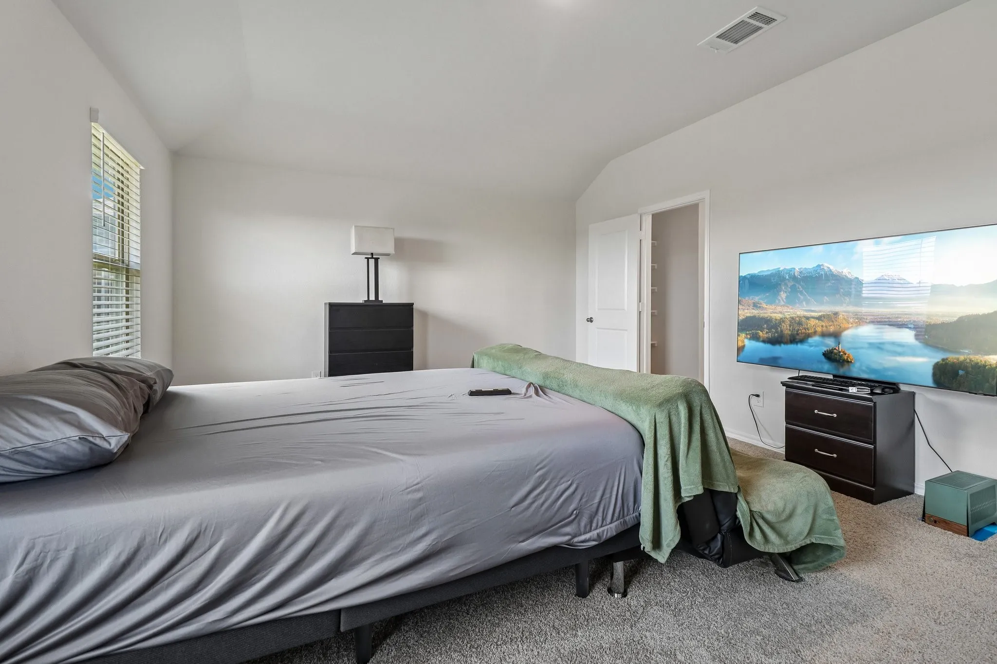 Carpeted room featuring a white ceiling, a rectangular window with horizontal blinds, and a white interior door