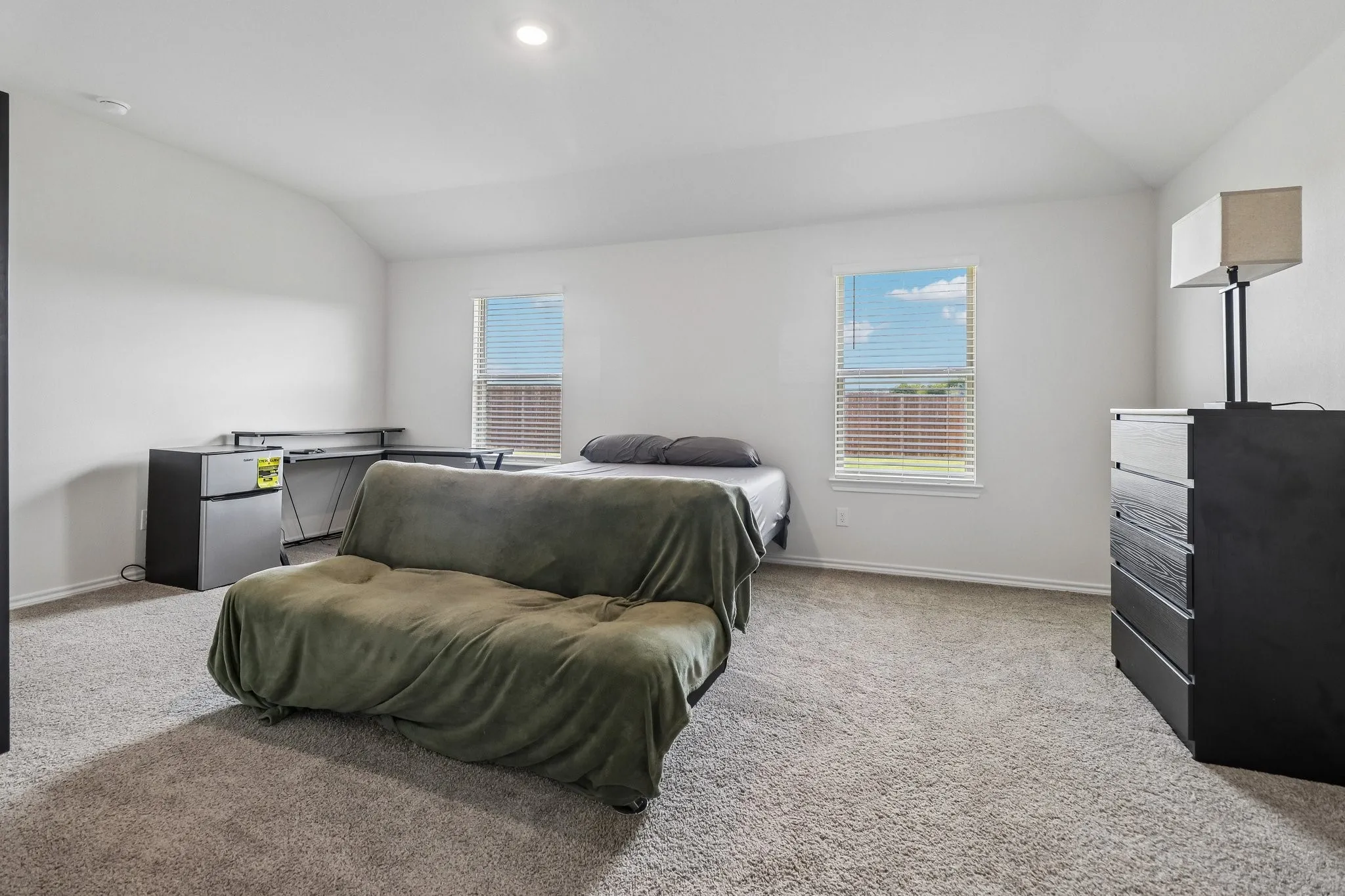 Carpeted room with vaulted ceiling and recessed lighting