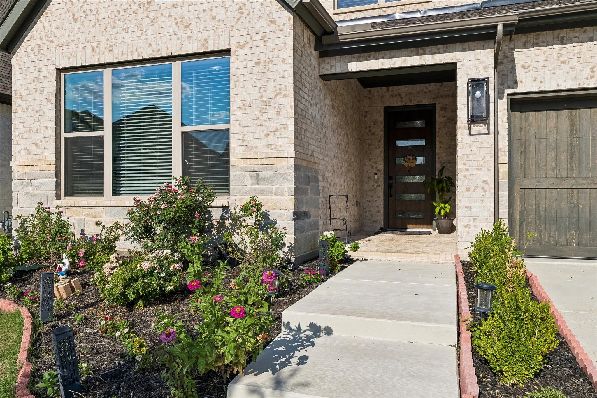 Brick exterior with stone accents and a contemporary dark wood entry door featuring horizontal glass panels