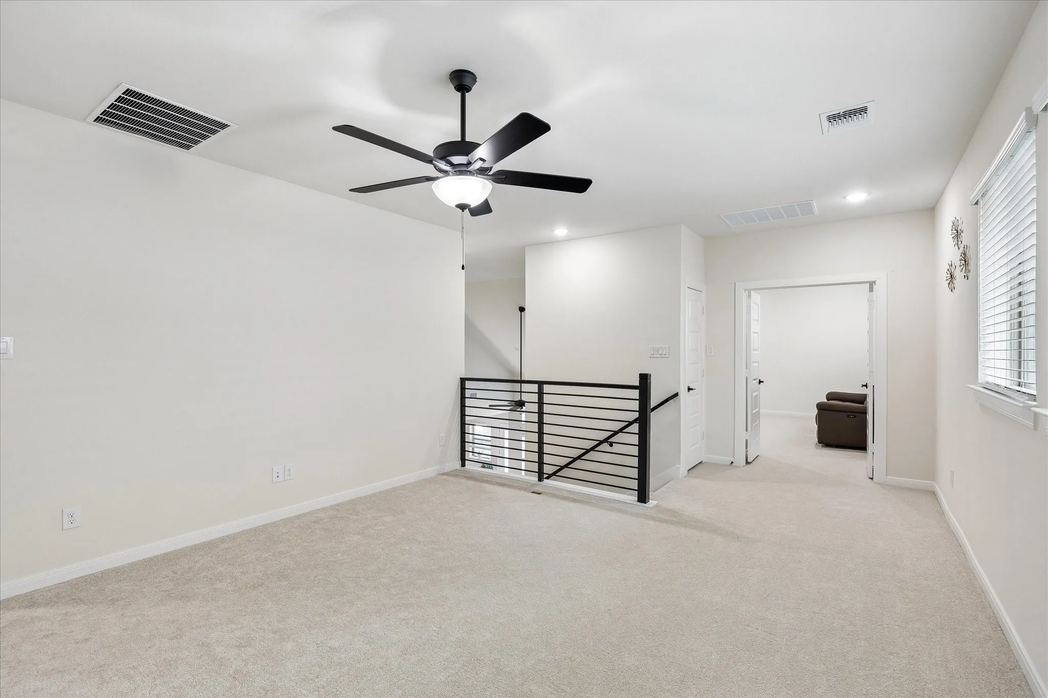 Spacious room featuring neutral carpeting, a ceiling fan, recessed lighting, and a white window with horizontal blinds
