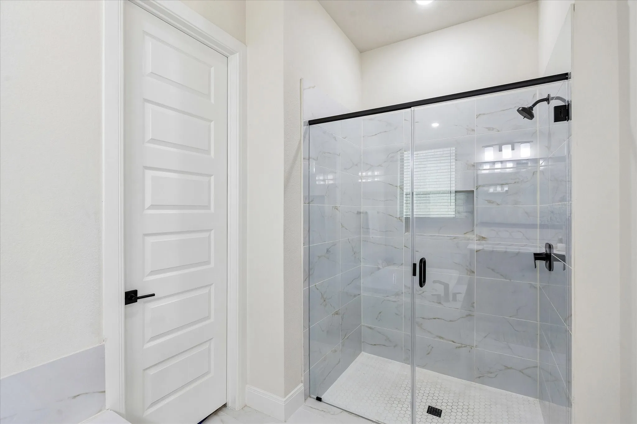 Glass-enclosed shower featuring large format tile surrounds and a hexagonal mosaic floor