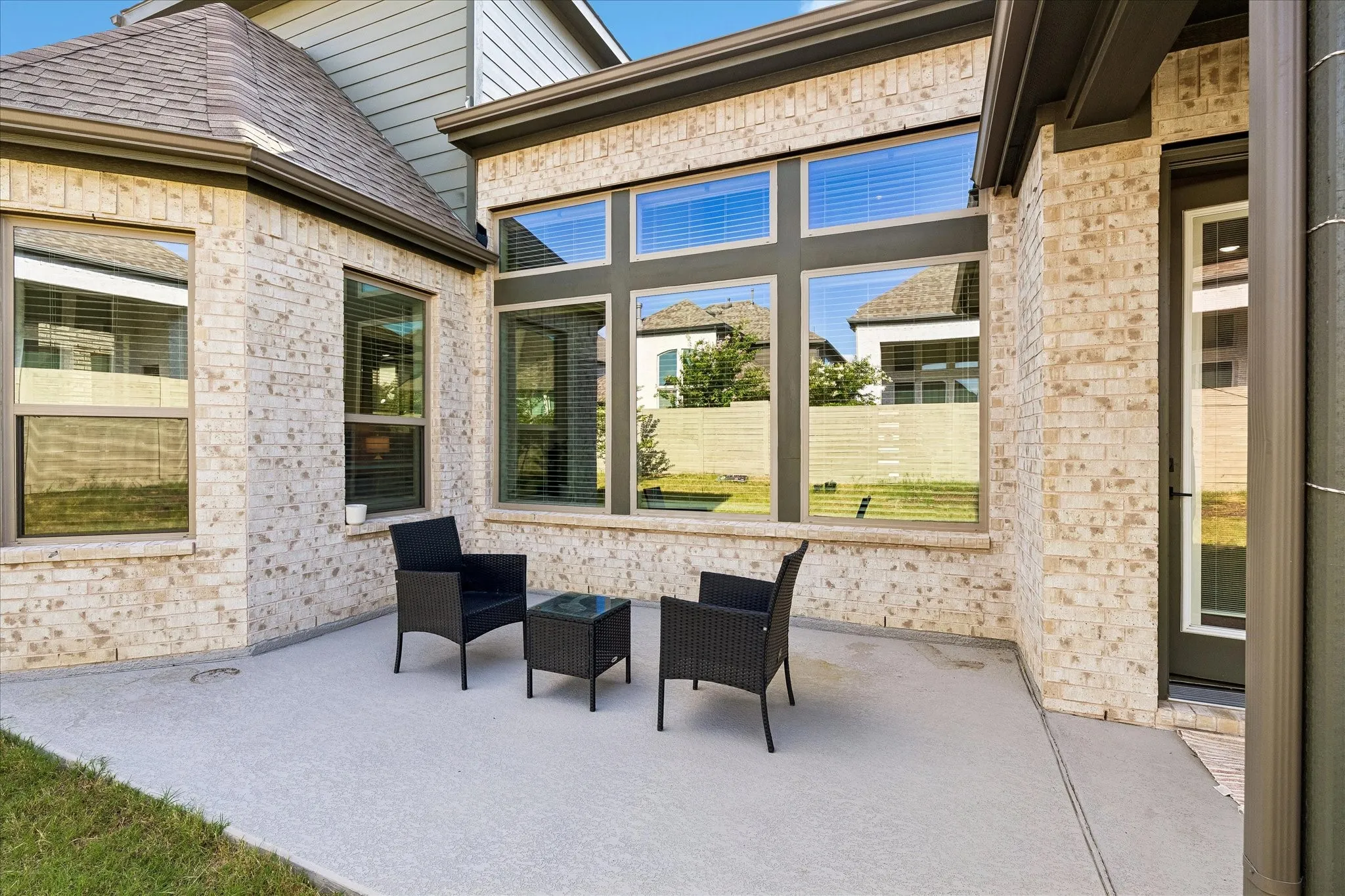 Expansive outdoor patio featuring light-toned brickwork and large windows with dark trim