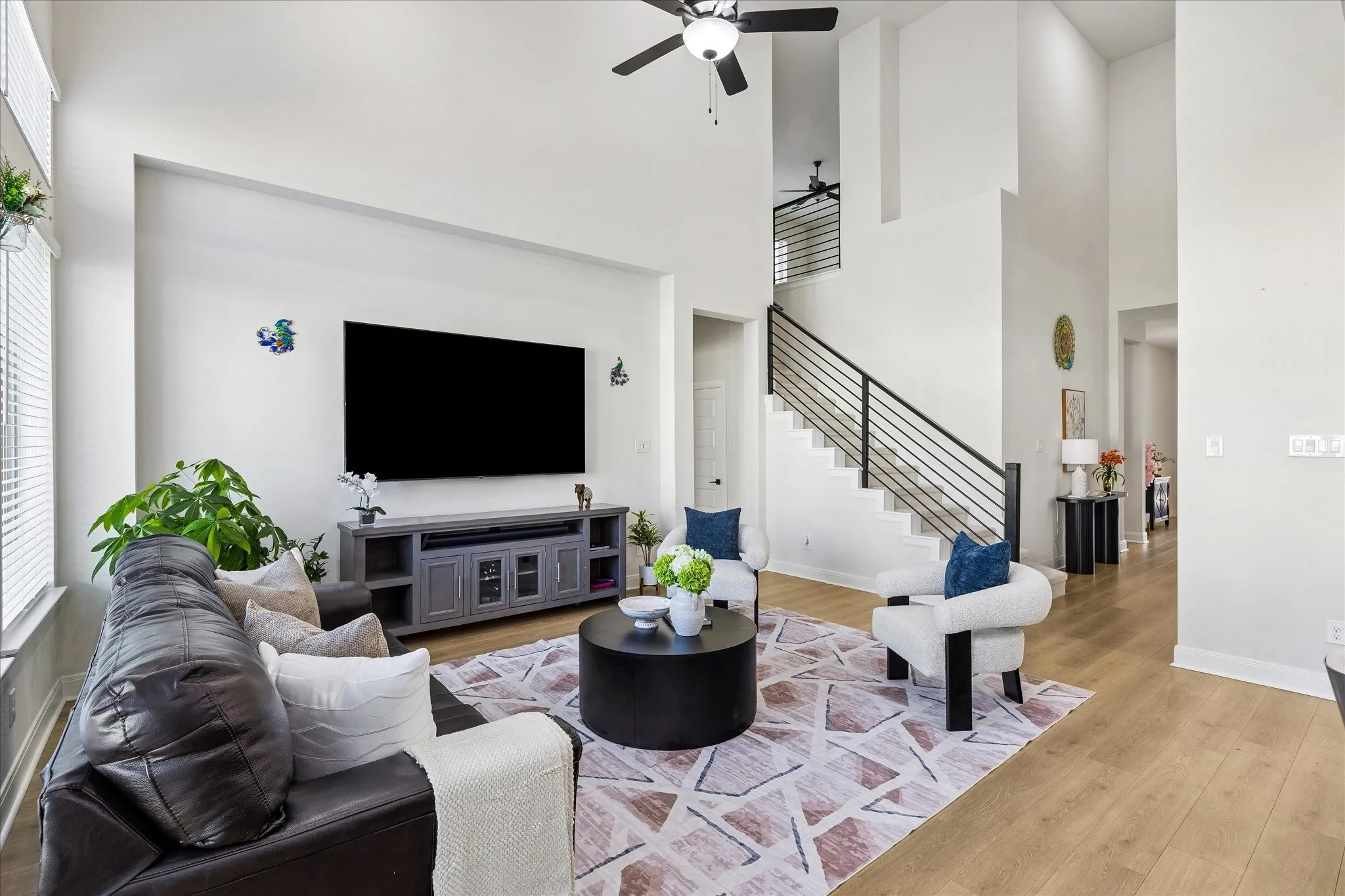 Living area featuring high ceilings, wood-finish flooring, and a contemporary ceiling fan