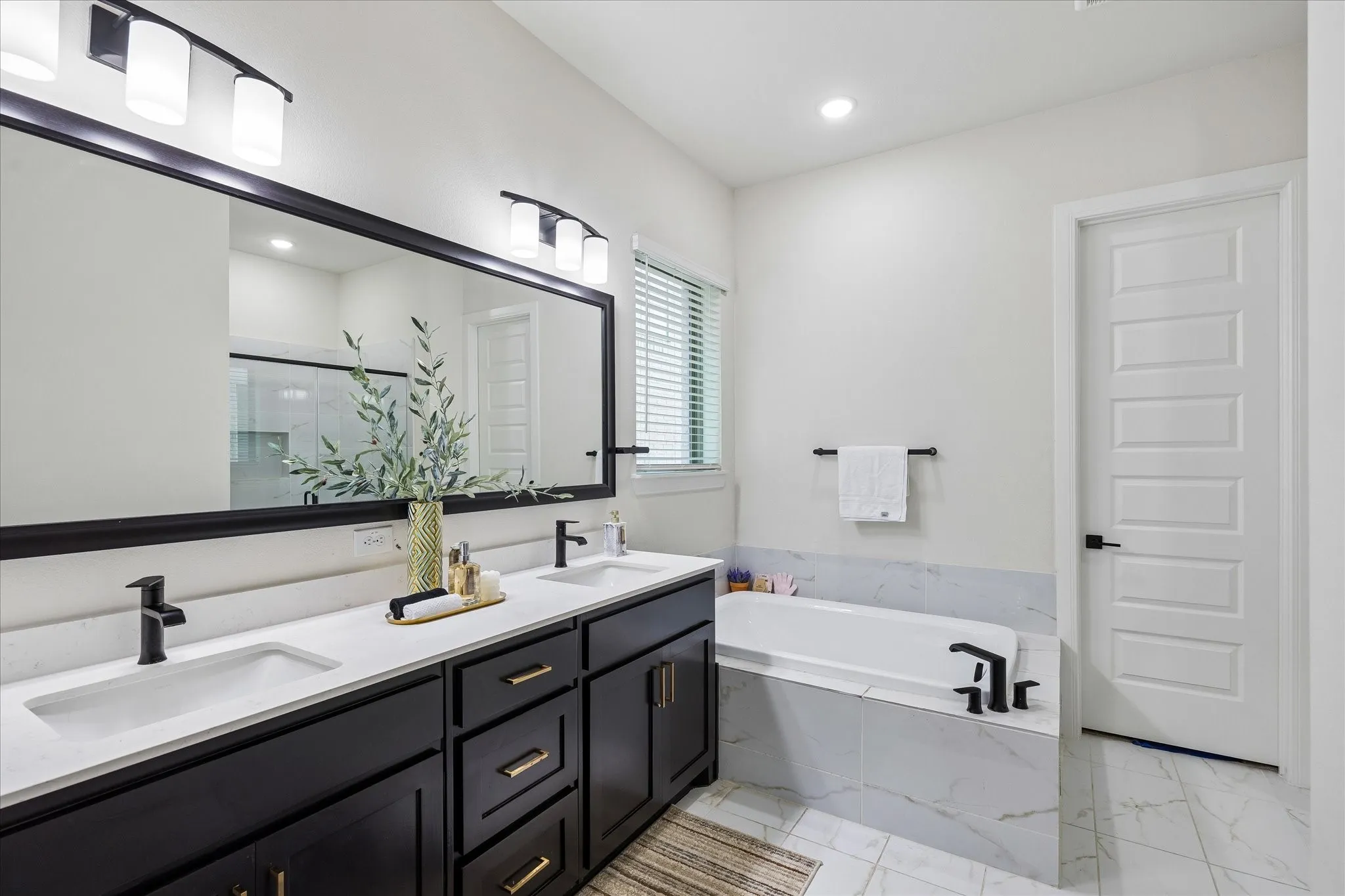 Bathroom featuring a double vanity with dark cabinetry, white countertops, and matte black fixtures